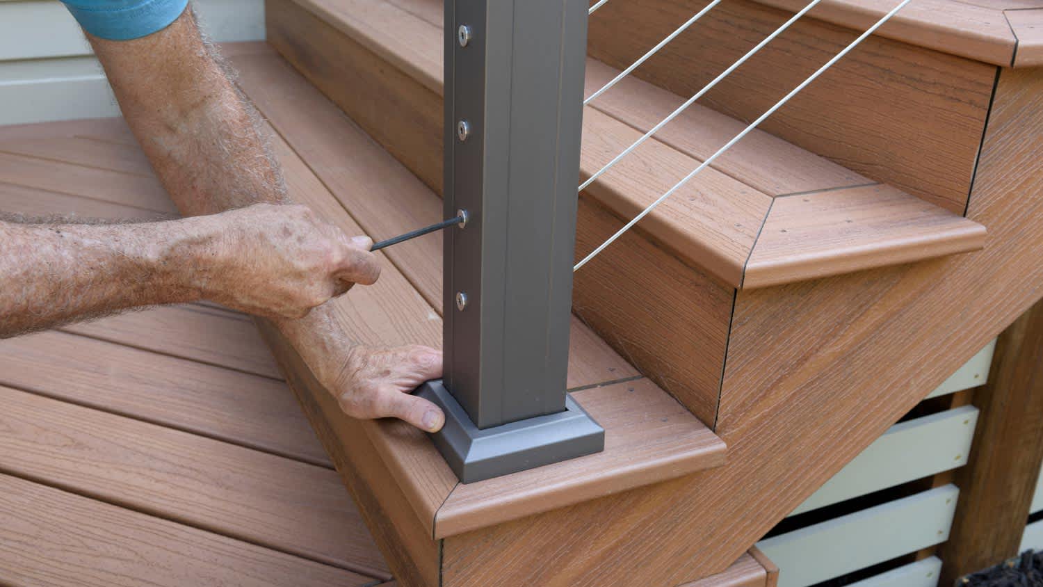 A man tighting screws on a deck railing