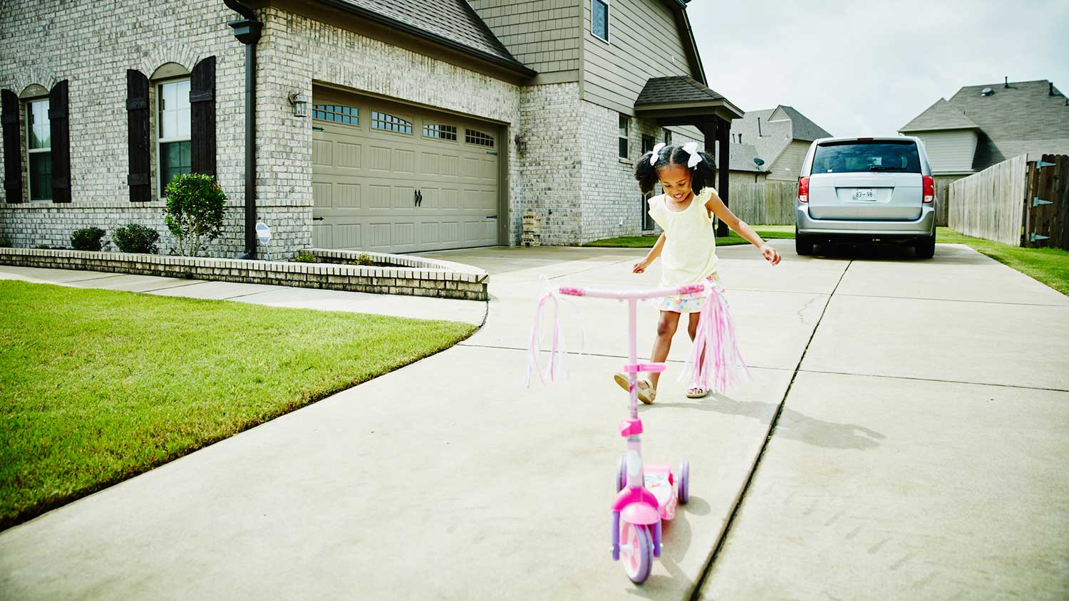 Girl playing with scooter on the driveway
