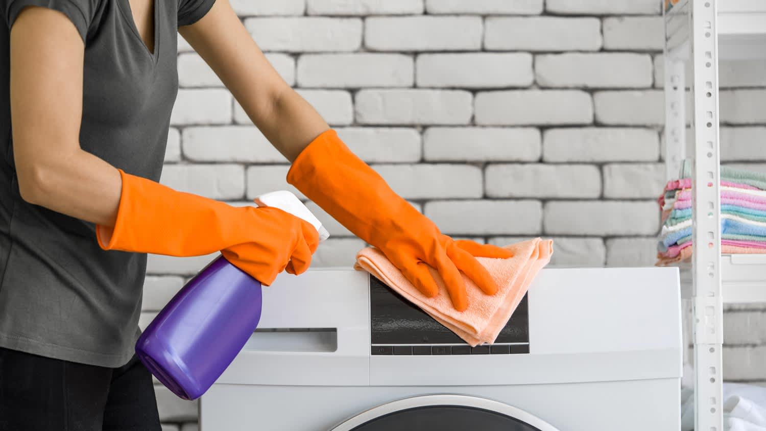 Close-up of a woman cleaning a washing machine with a cloth