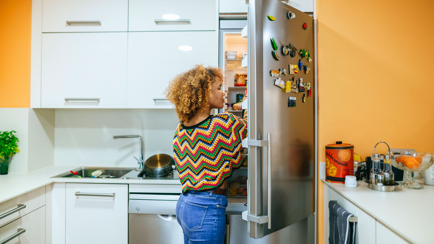 A young woman looking inside a refrigerator