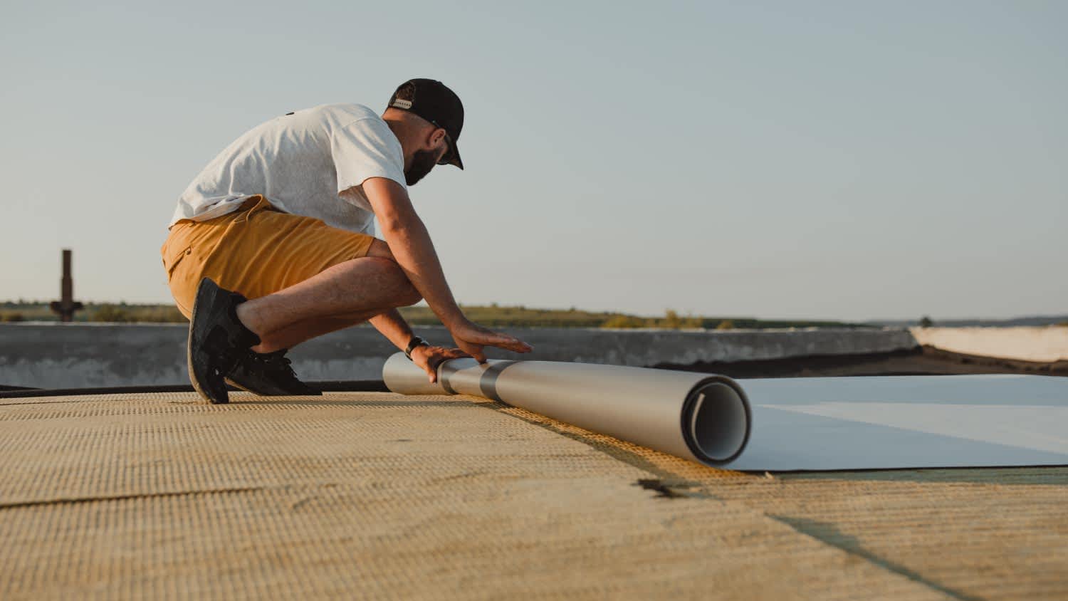 Worker installing pvc membrane roller on roof