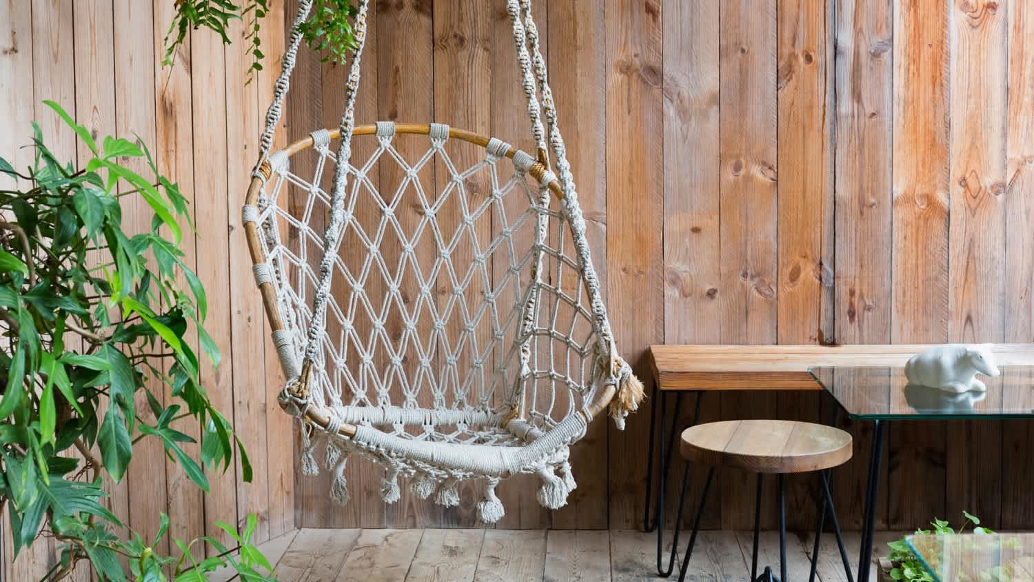 A hanging chair in a covered in plants wooden patio