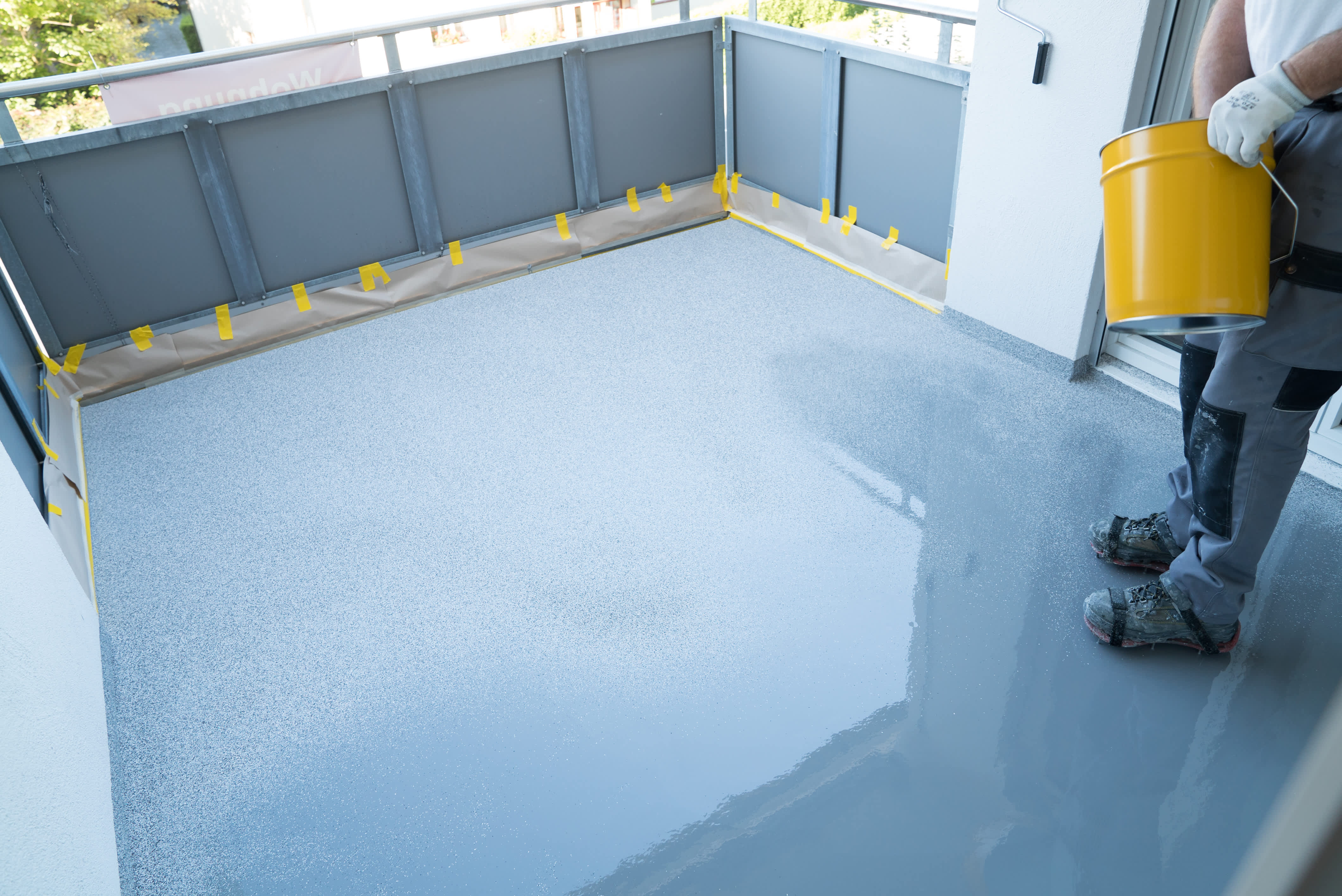 Worker installing epoxy floor coating to balcony floor