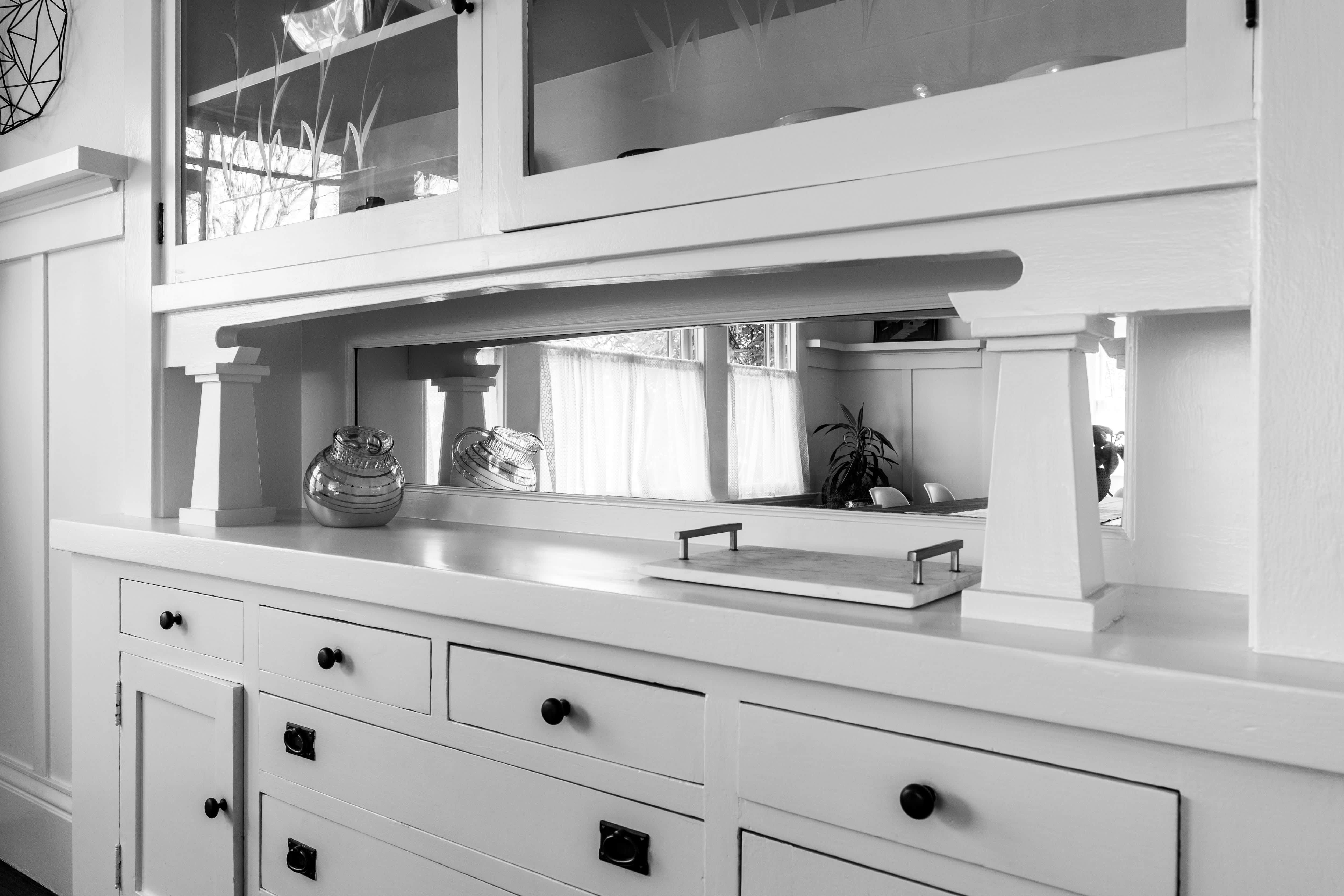A gray butler’s pantry with a glass backsplash