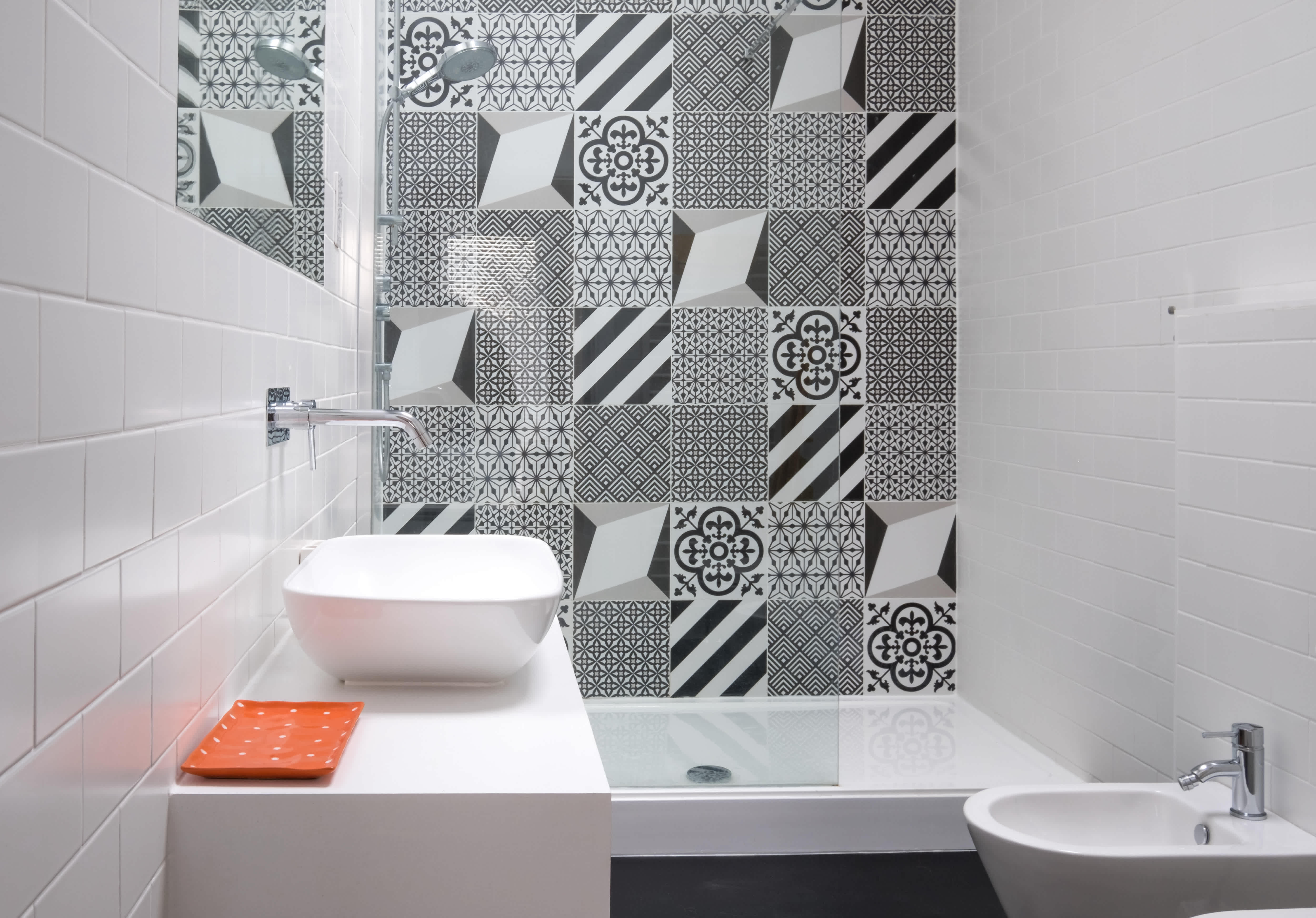 A walk-in shower with a black-and-white ceramic tile accent wall