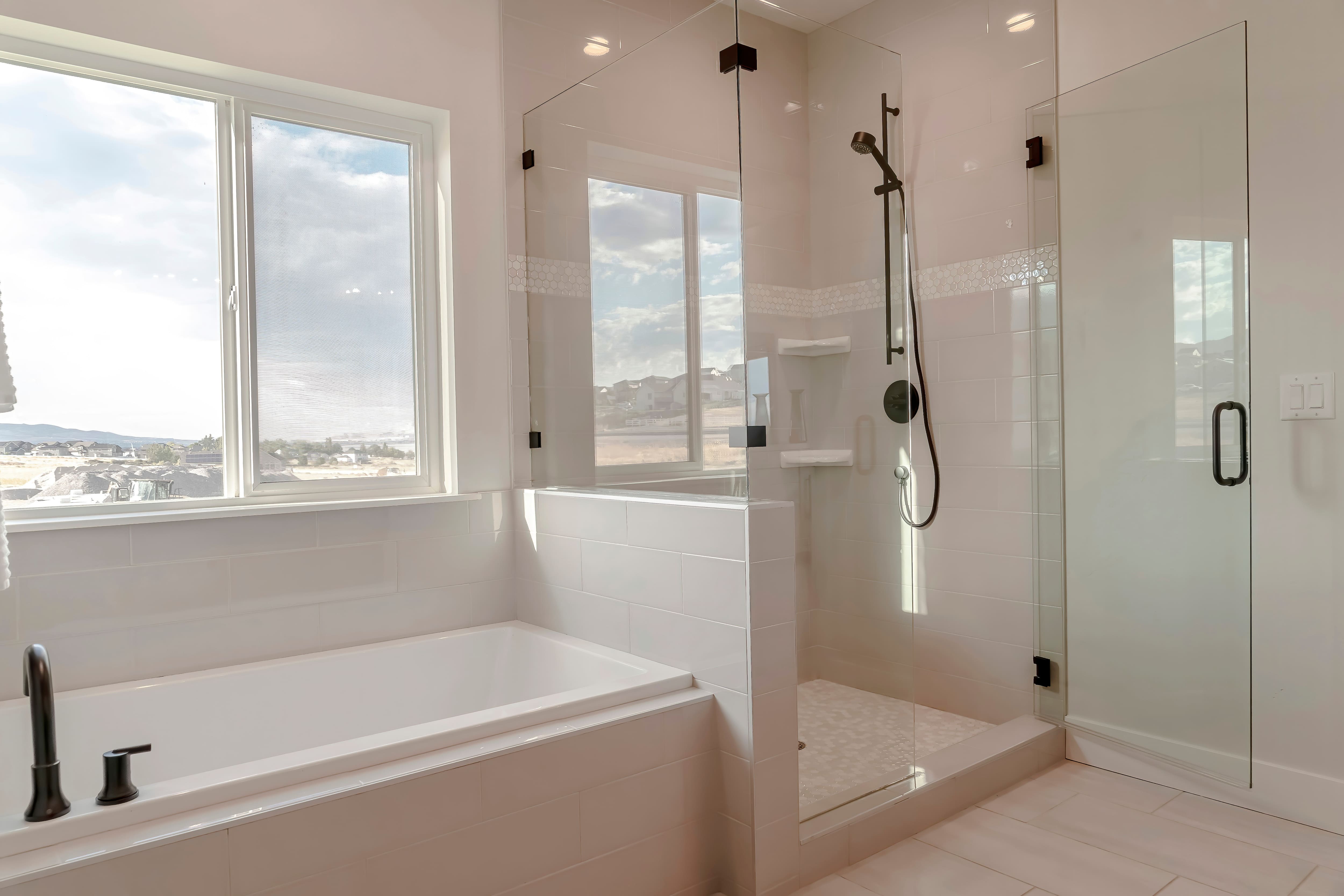 A built-in bathtub with a corner walk-in shower with a half-glass enclosure
