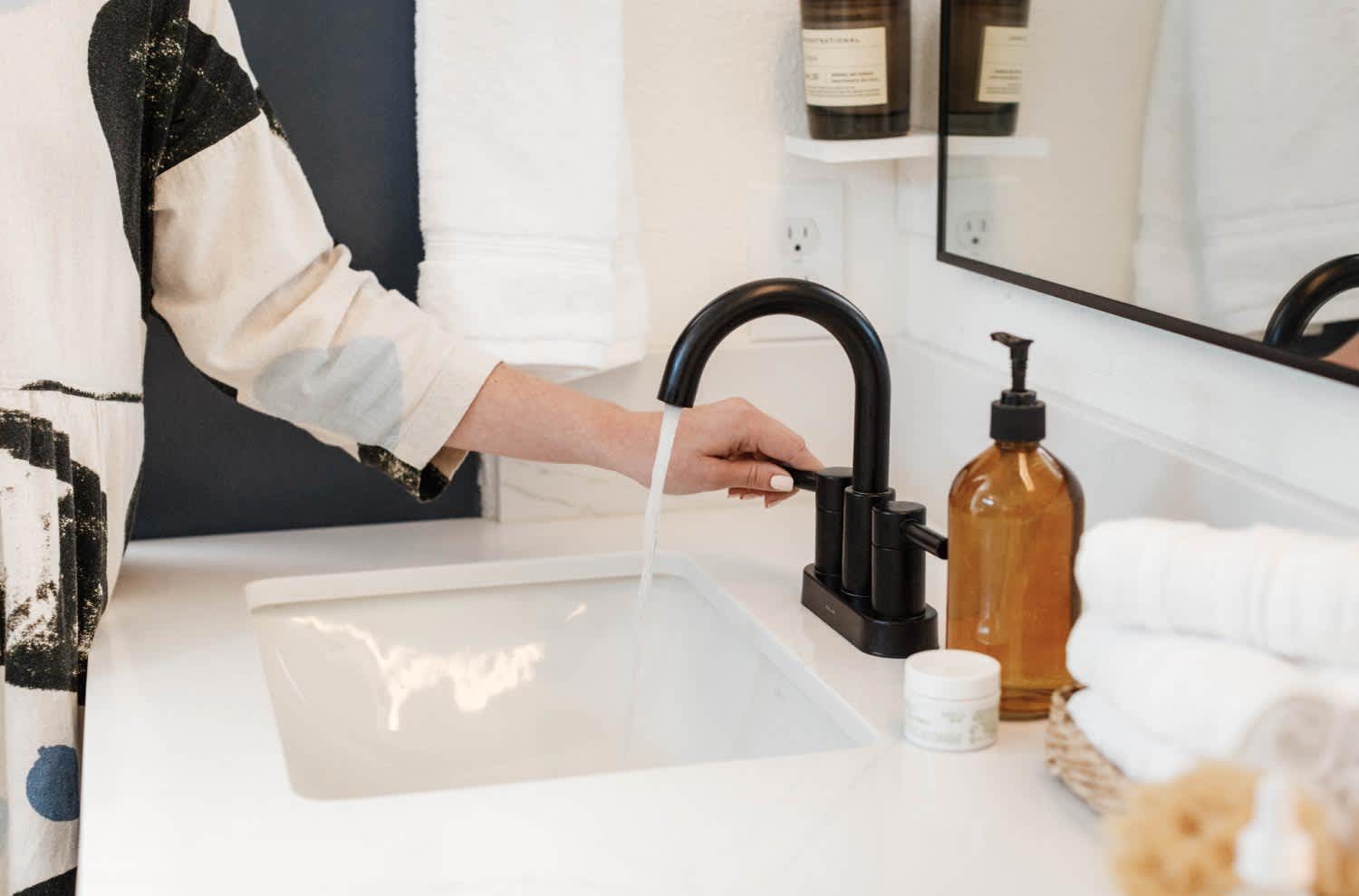 woman turning on black faucet