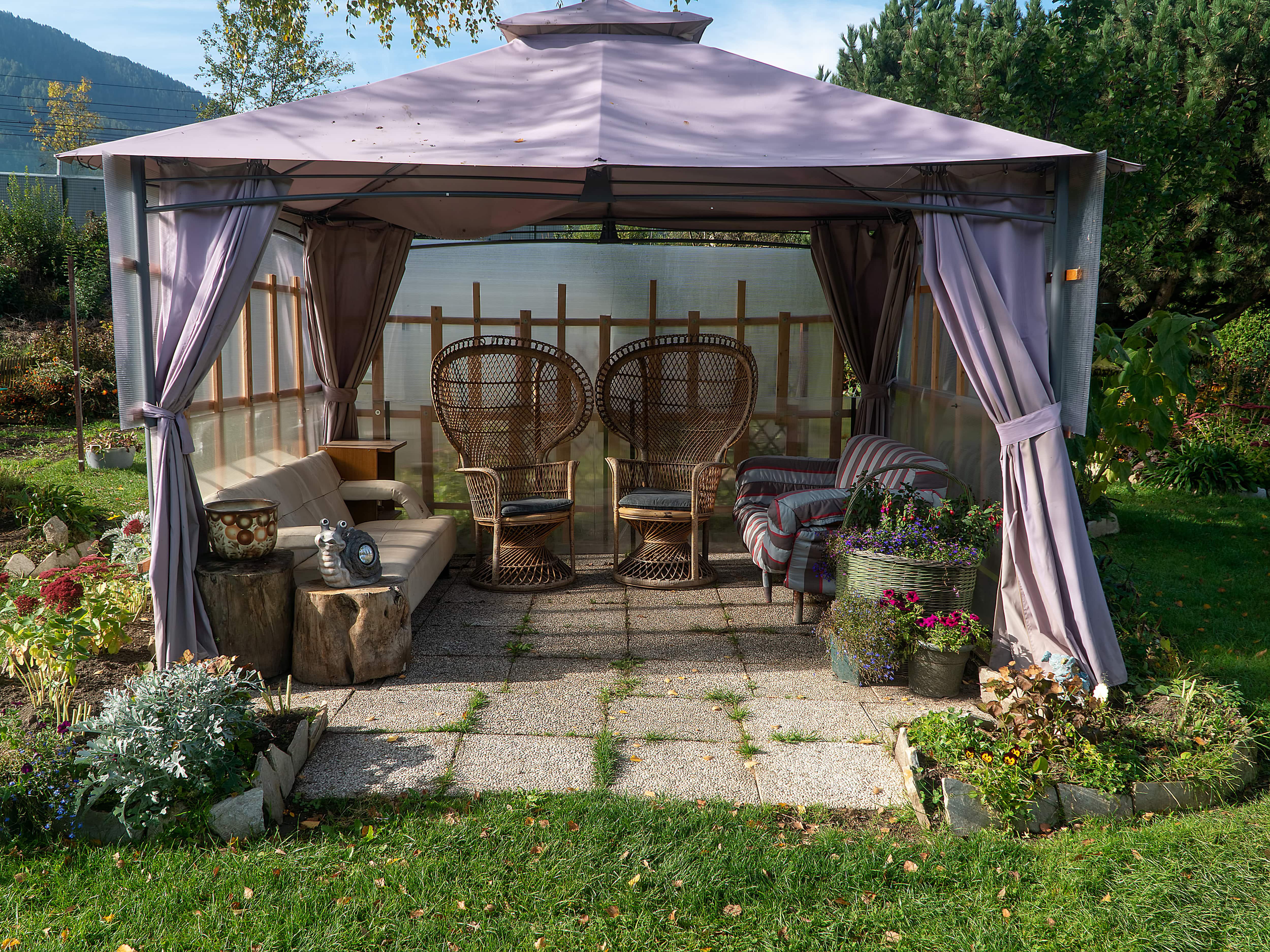 Soft-roof gazebo with chairs and couch underneath