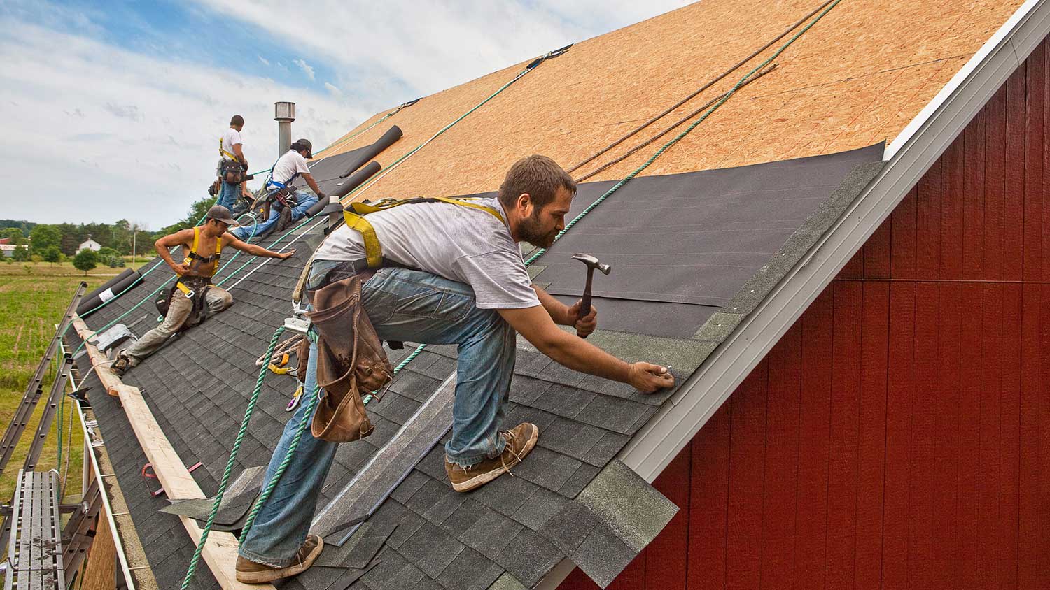 Group of workers installing new roof shingles