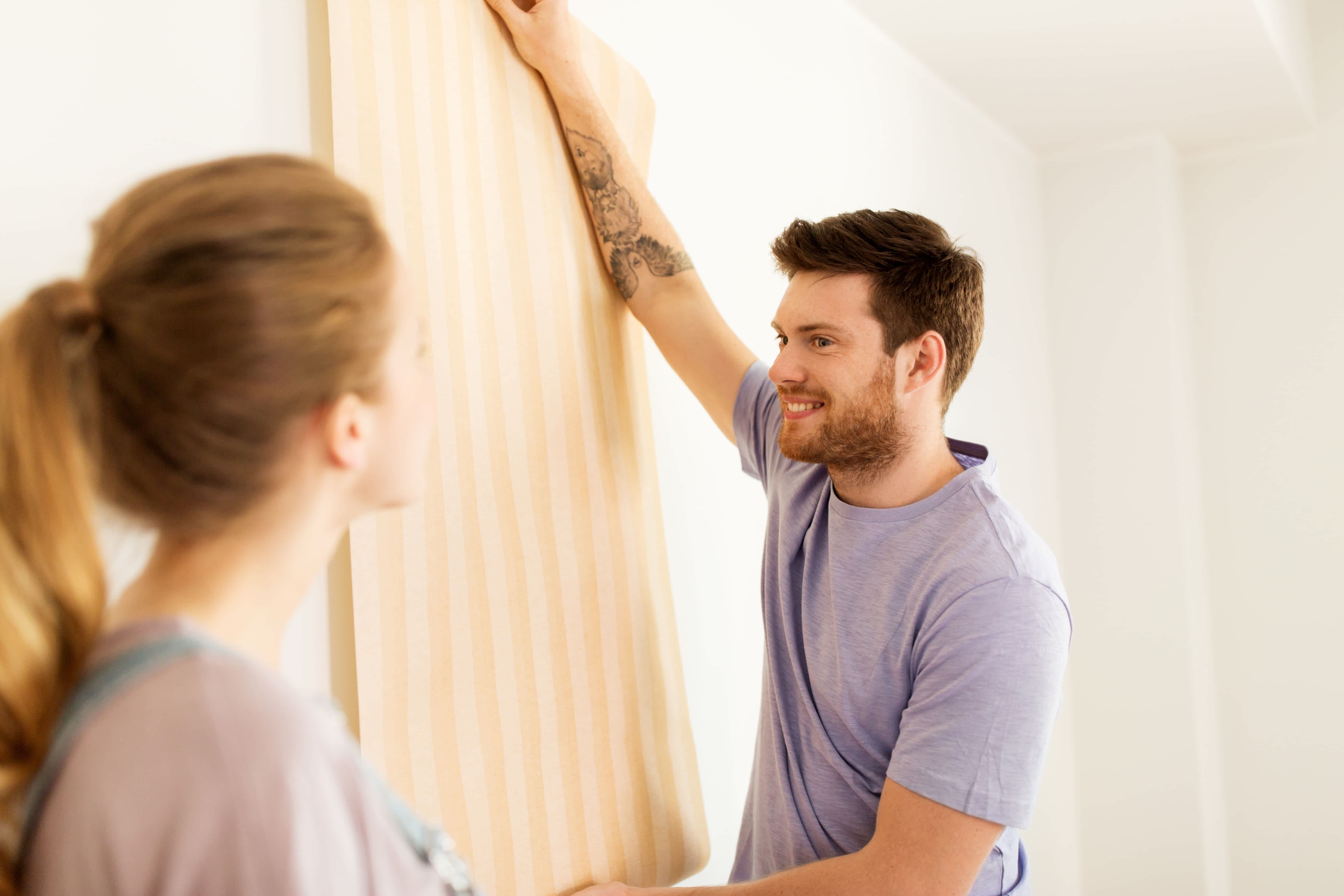 Man and woman sampling new wallpaper in home