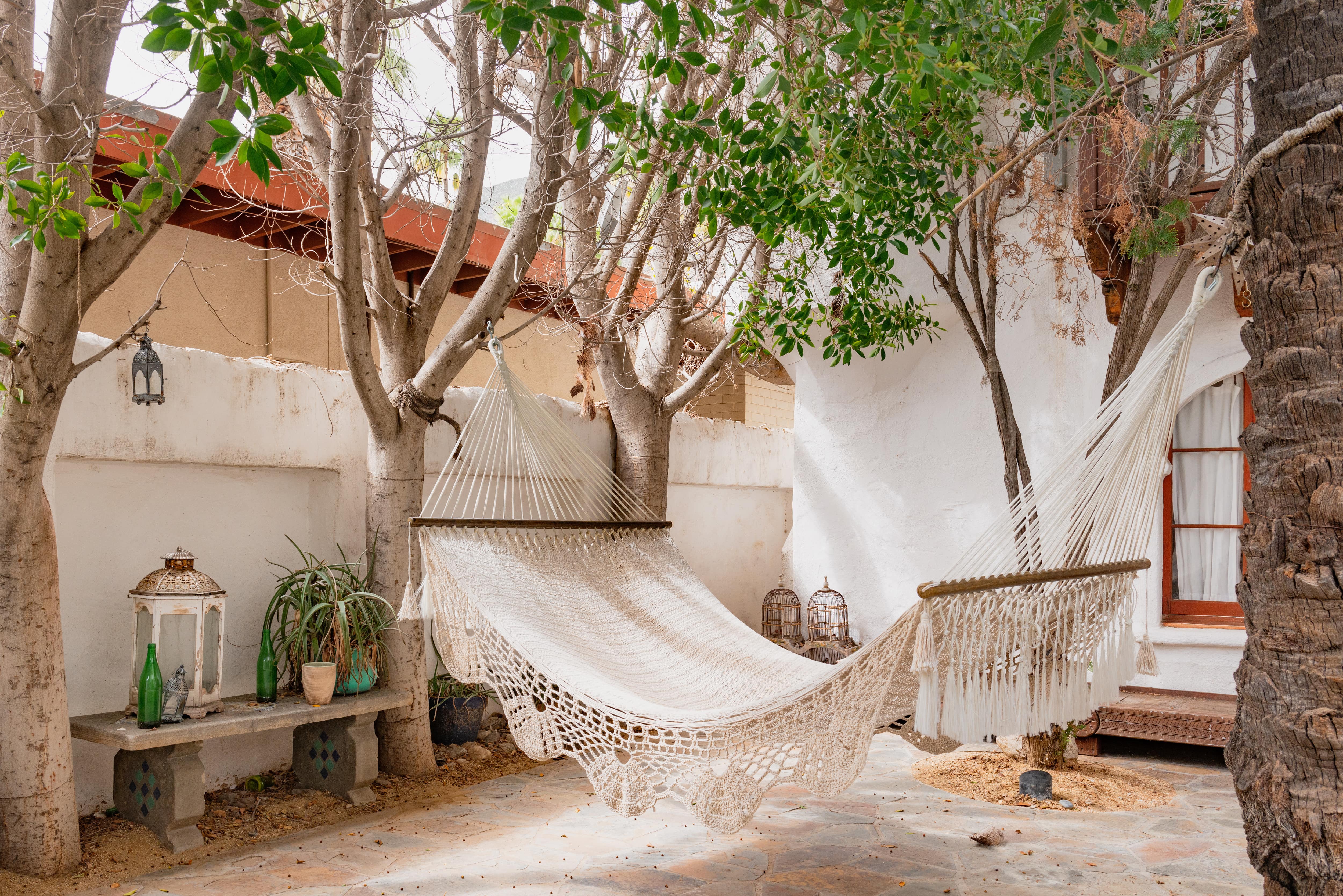 Macrame hammock suspended from trees on back patio