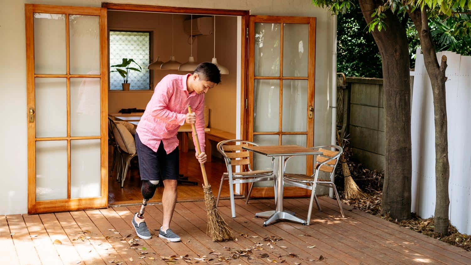 A man sweeping leaves a wooden patio