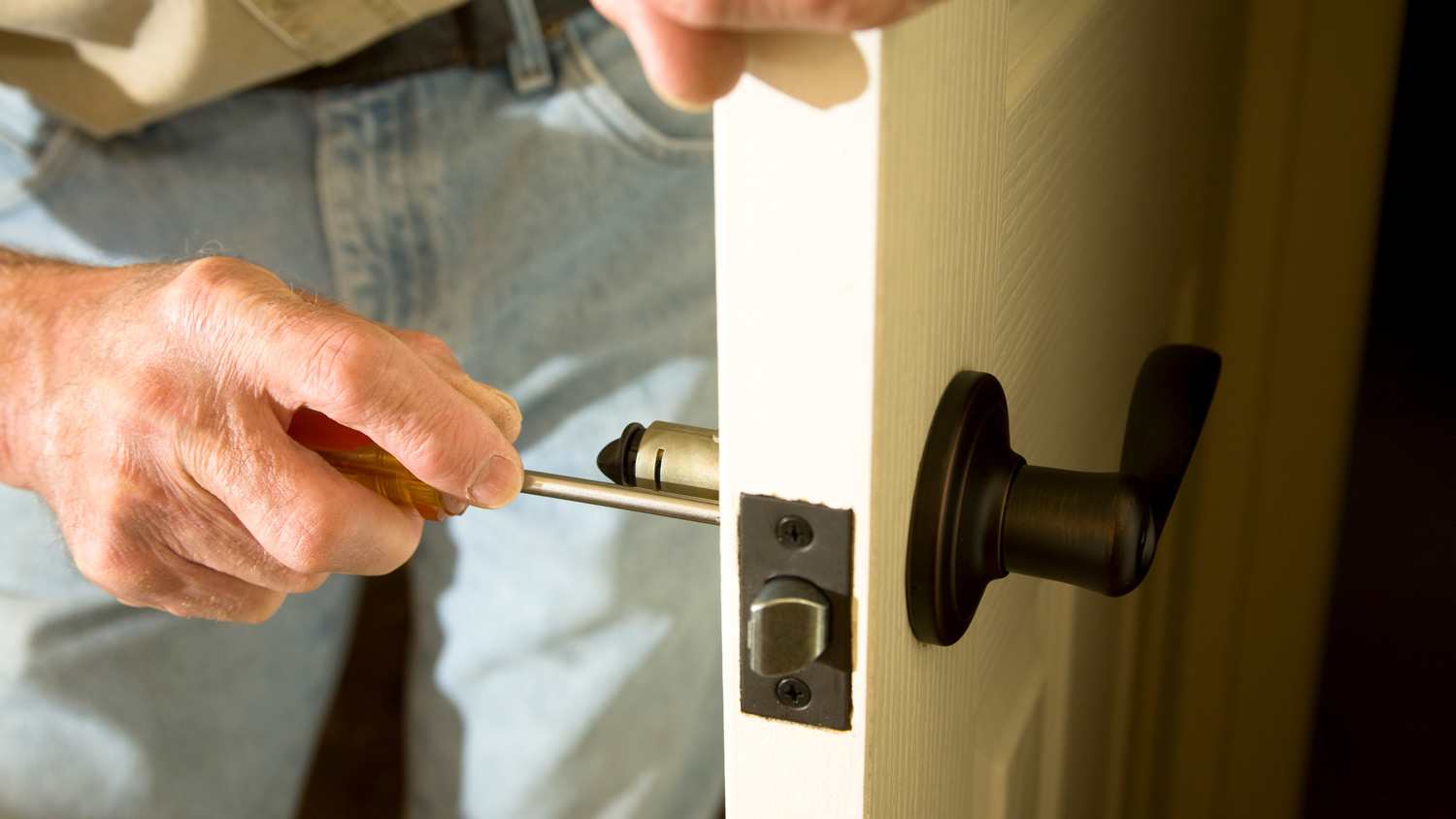 A man checking door lock screws