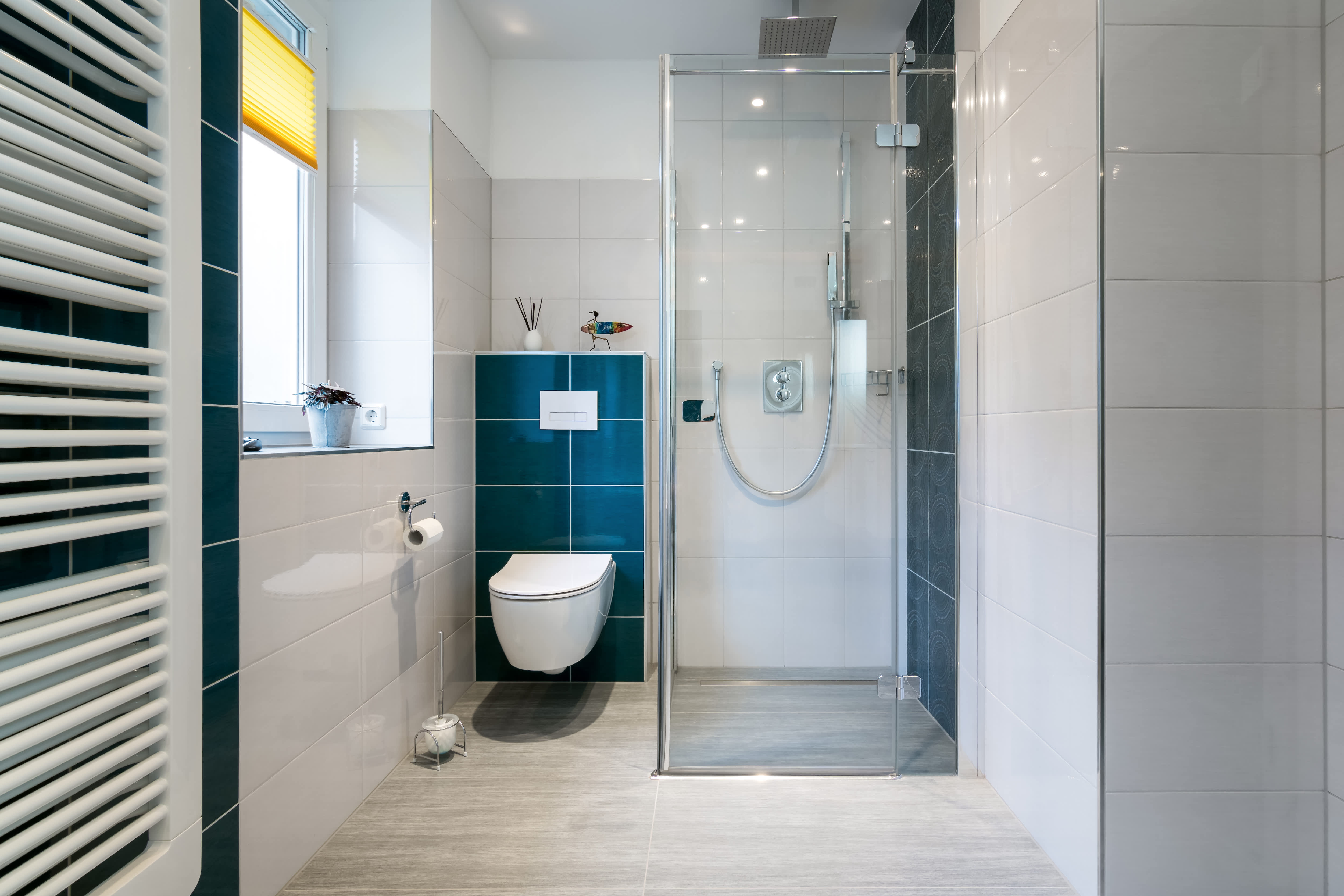 A corner walk-in shower in a small bathroom with dark blue tile