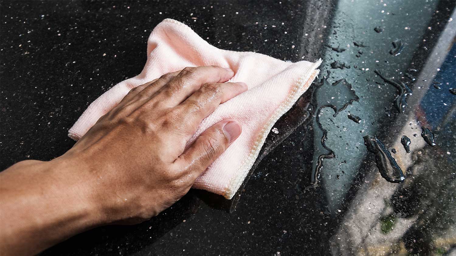 A hand wipes a spill on a countertop