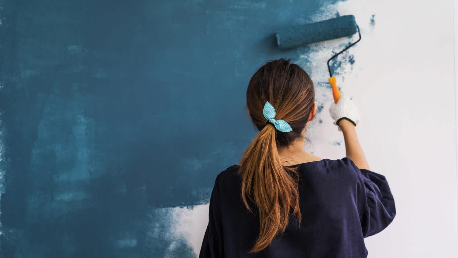A woman painting an accent wall with a paint roller