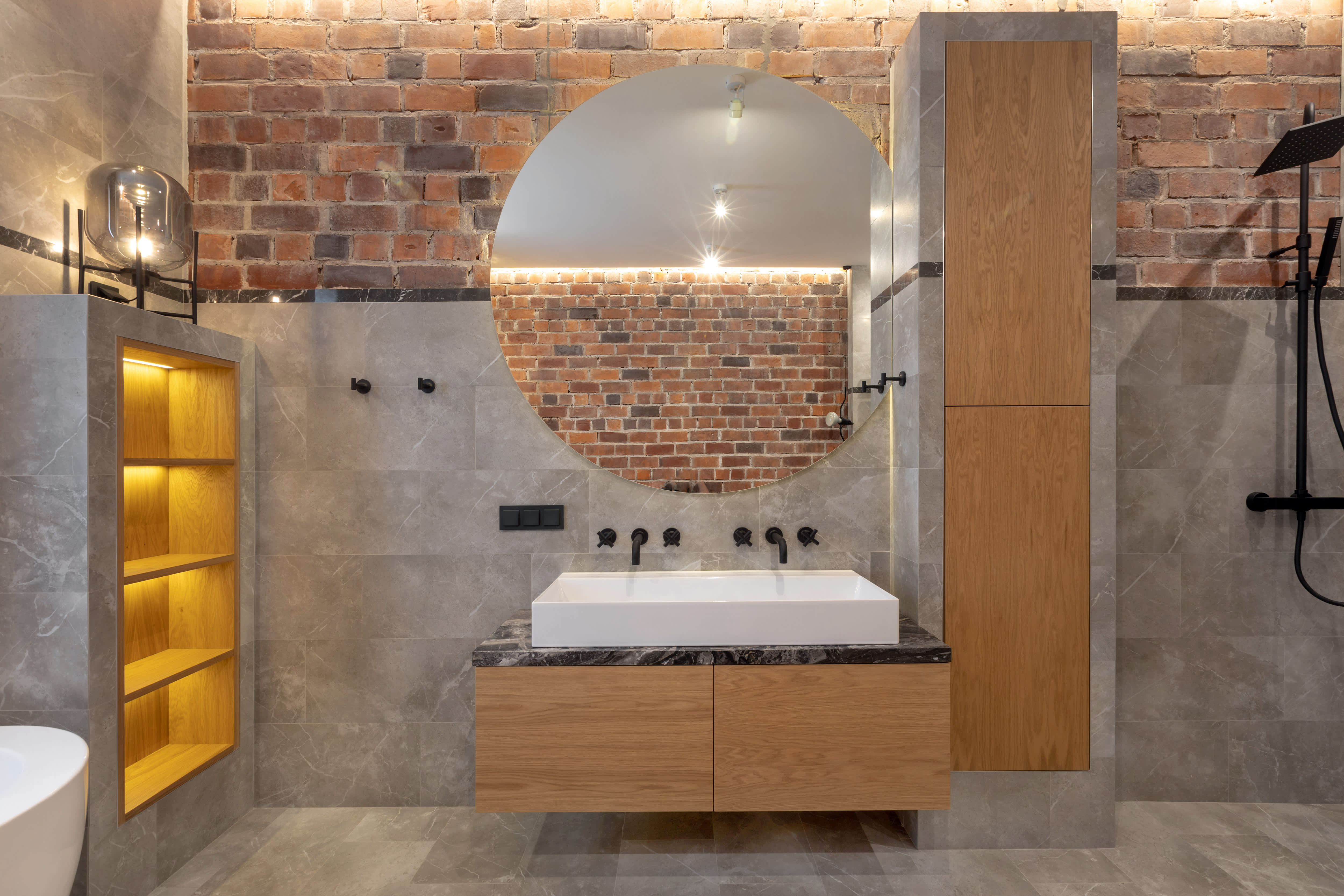 A bathroom with gray slate walls, an open shower, and brown vanity