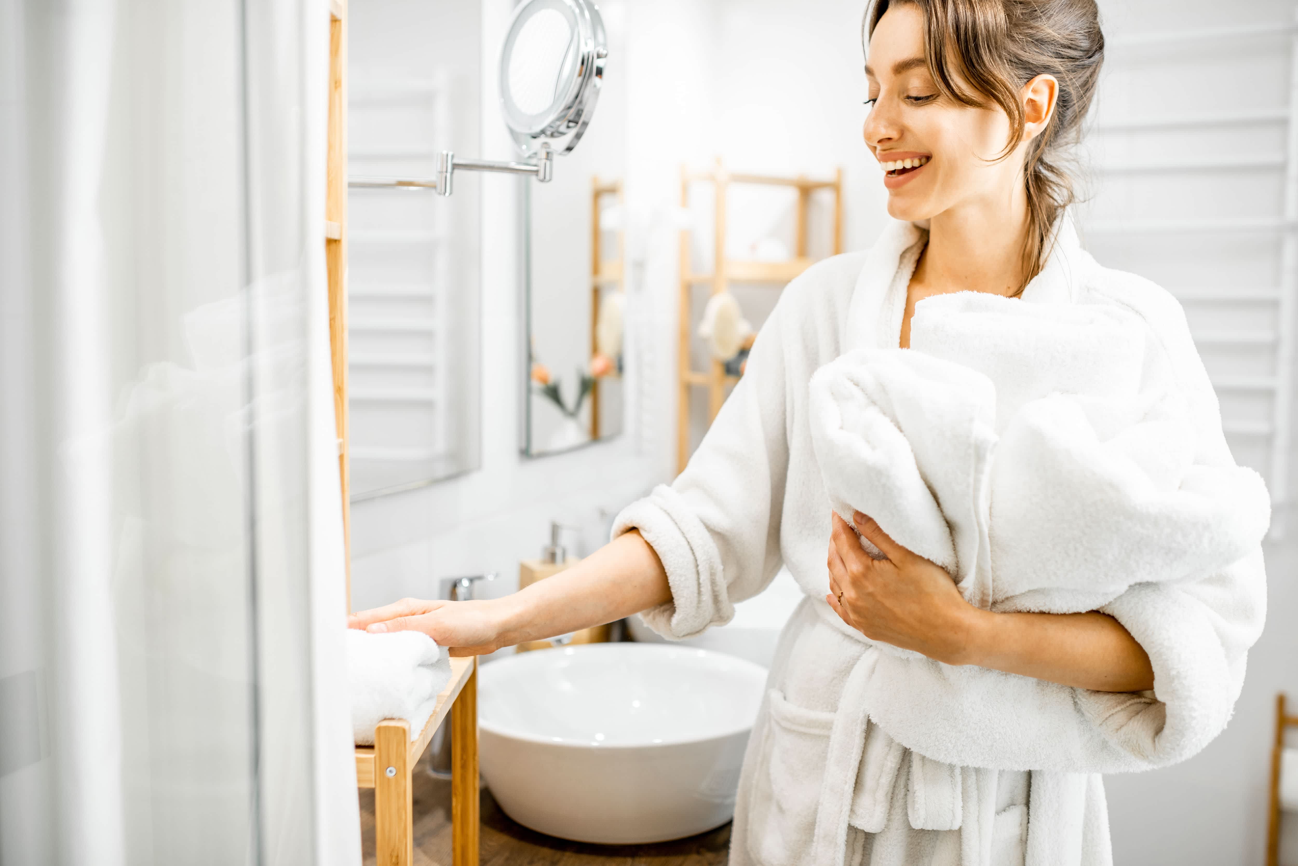 A woman in a bathrobe putting away towels