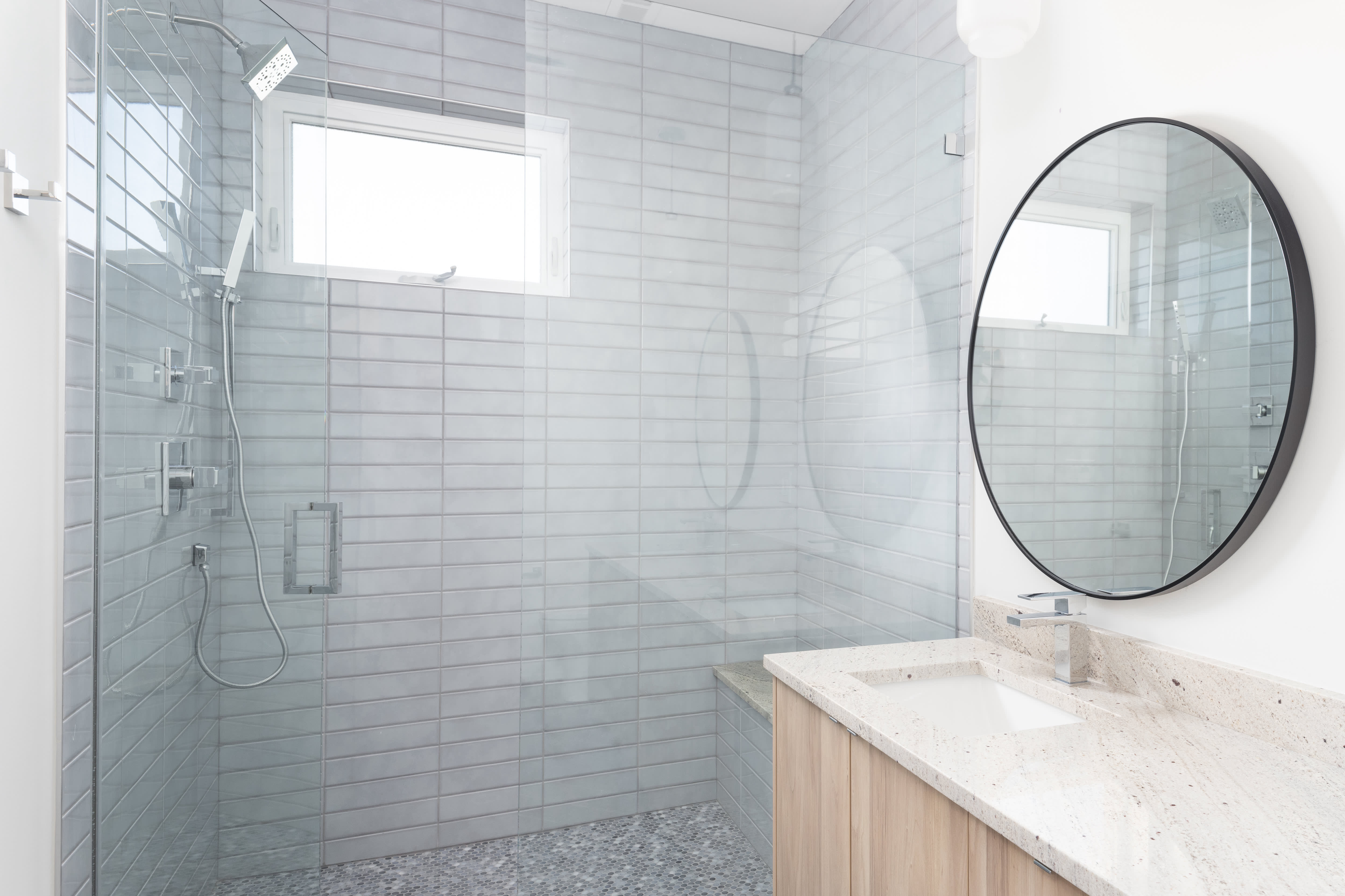 A white walk-in shower with a hinged door and white subway tile