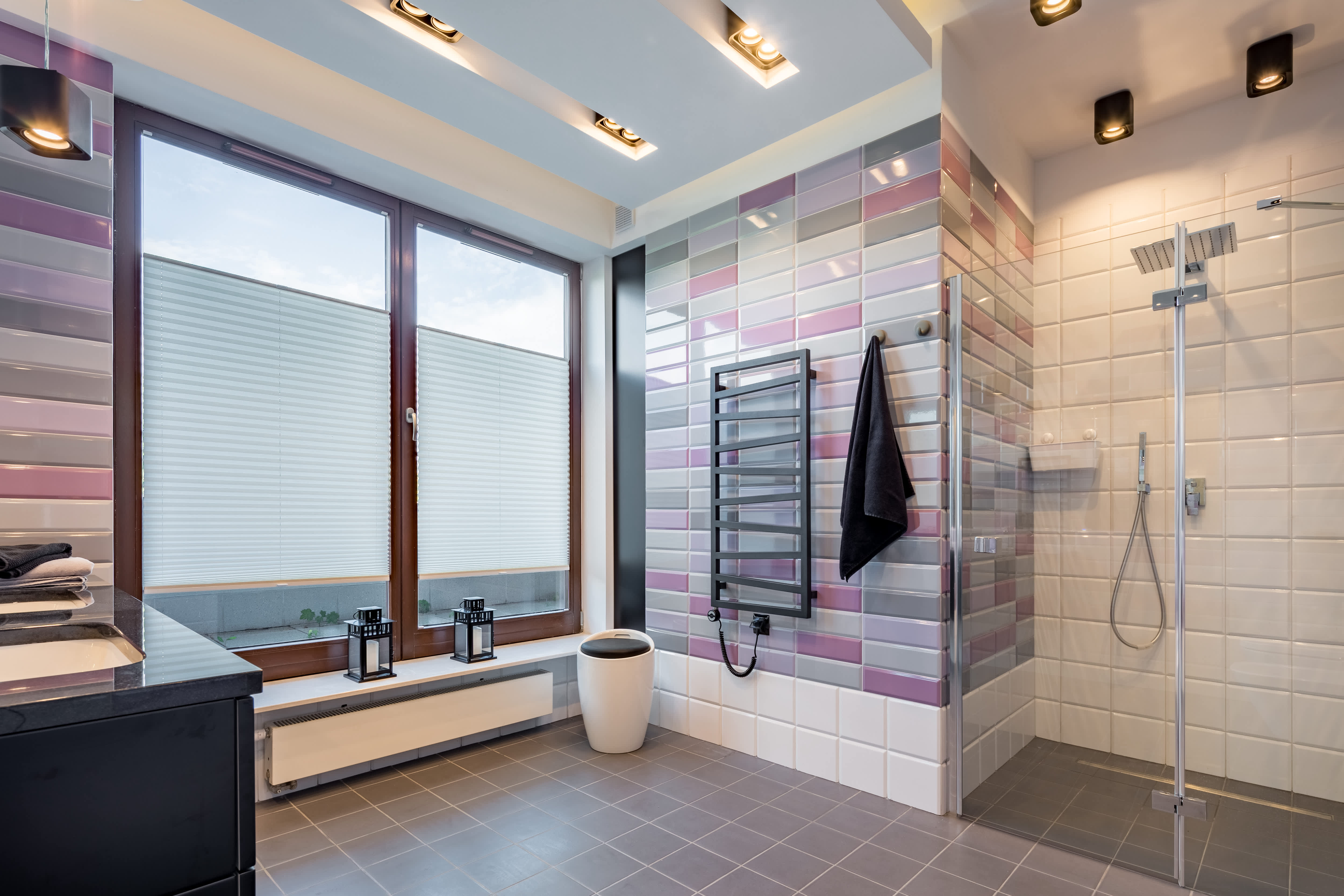 A purple-and-white bathroom with a walk-in shower, overhead lighting, and large windows