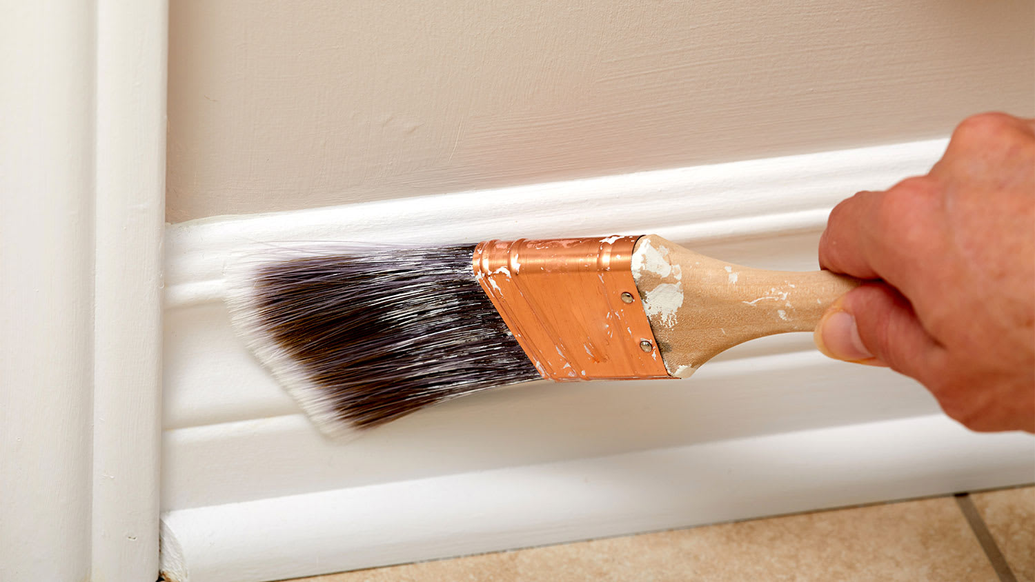 A view of white baseboard being painted