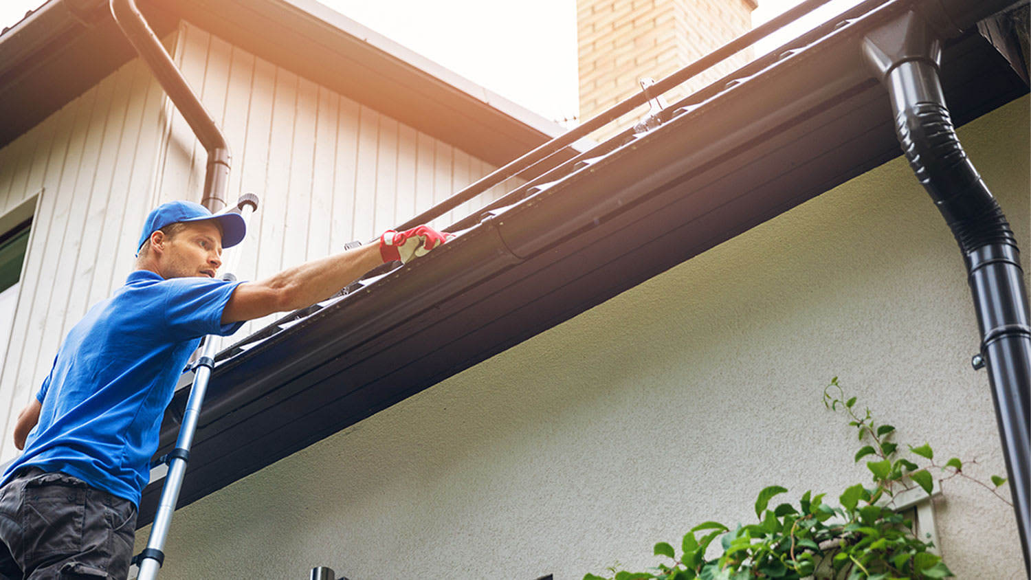 A man installs gutters on a house