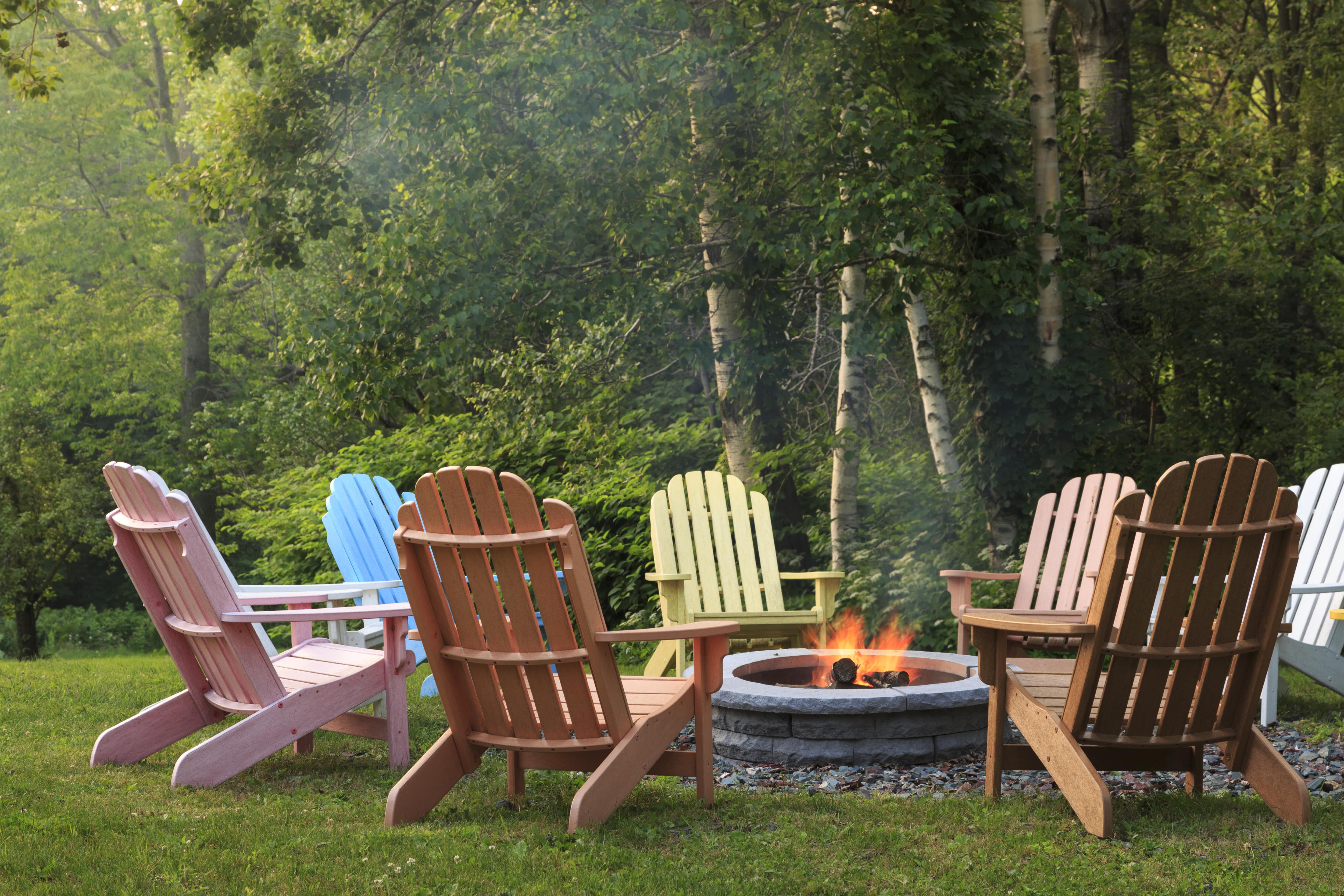 Adirondack chairs painted different colors around fire pit