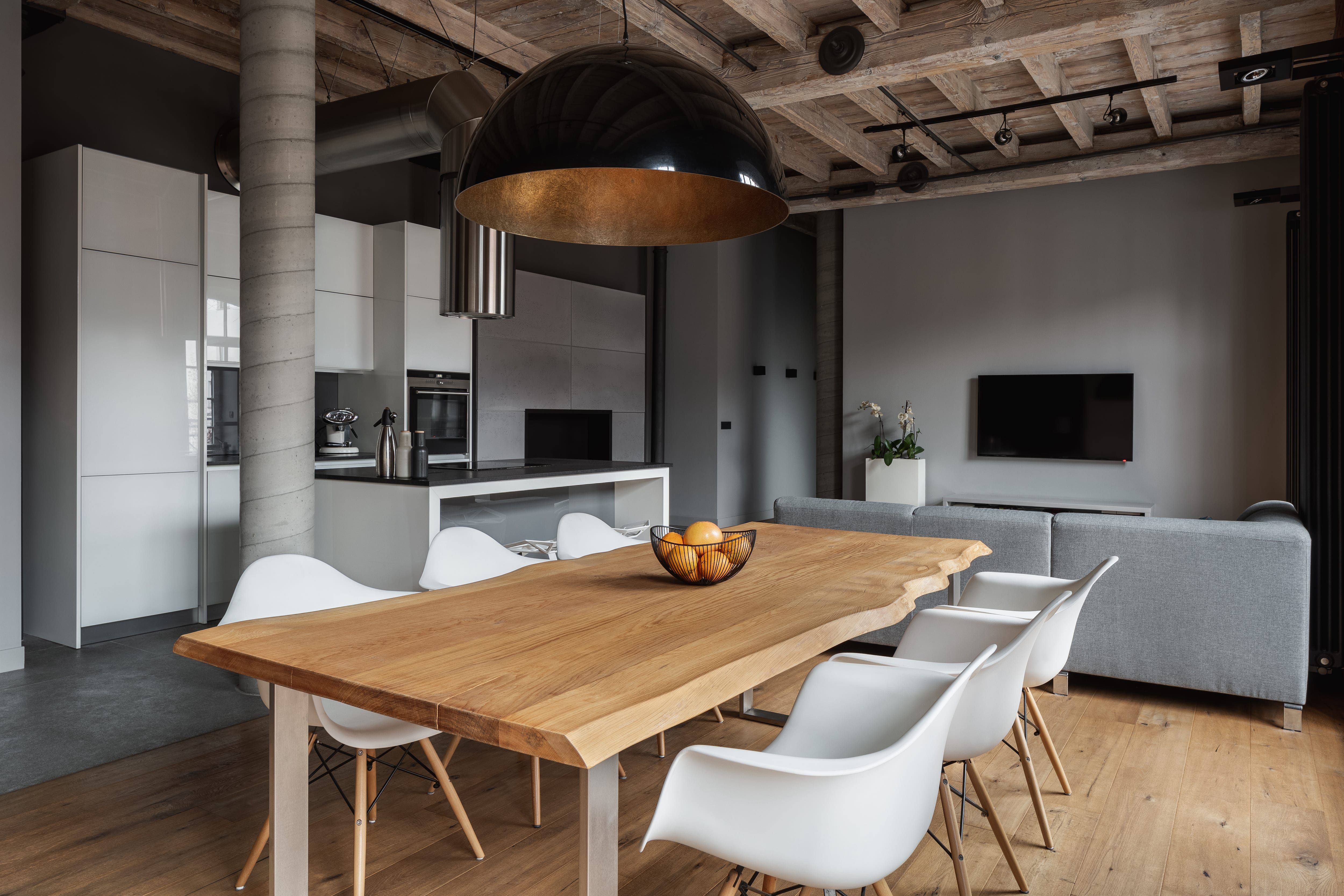 Modern industrial dining room with live-edge table, white modern chairs, and oversized black pendant light