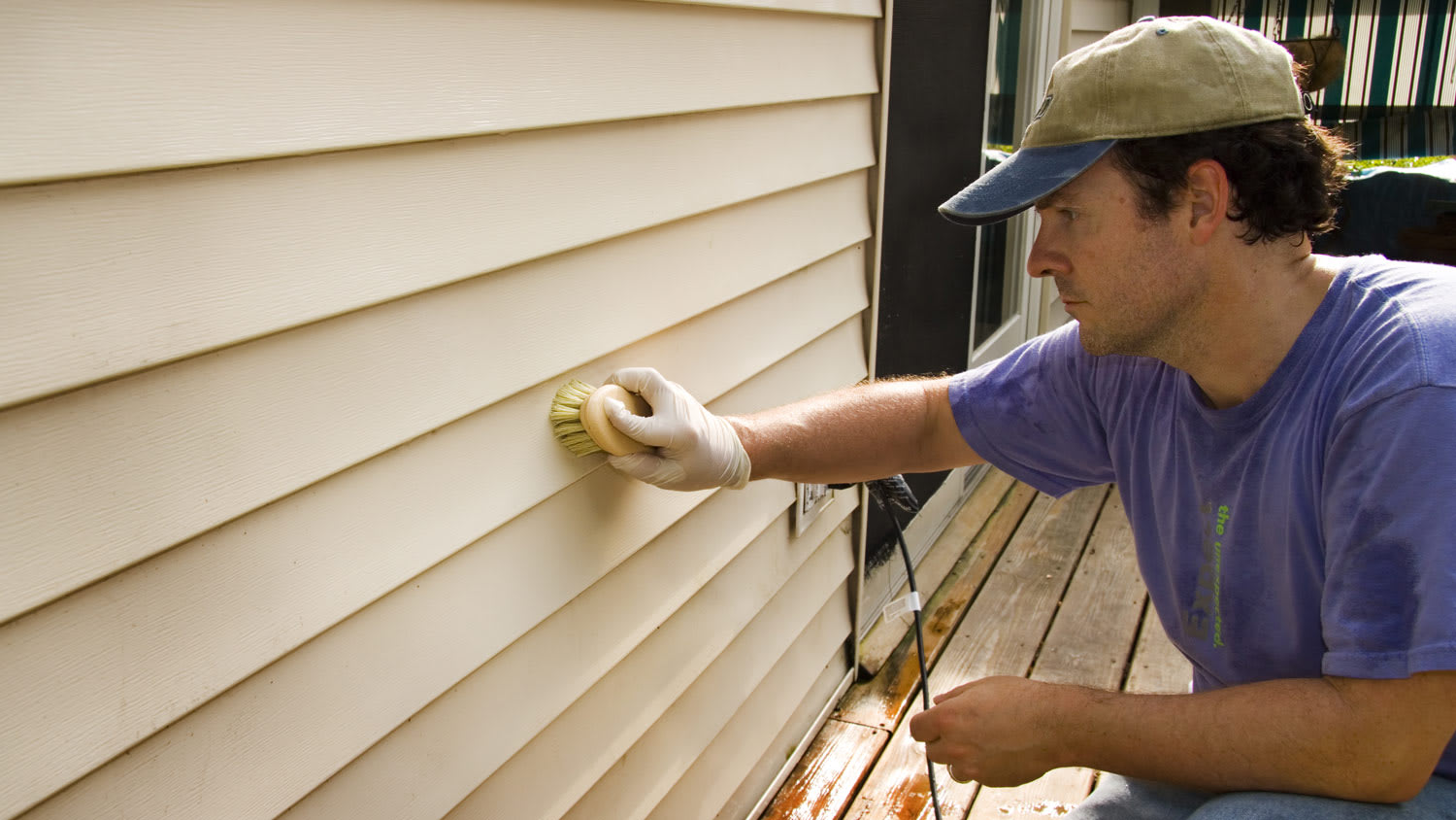 A man repairing vinyl siding of a house exterior wall