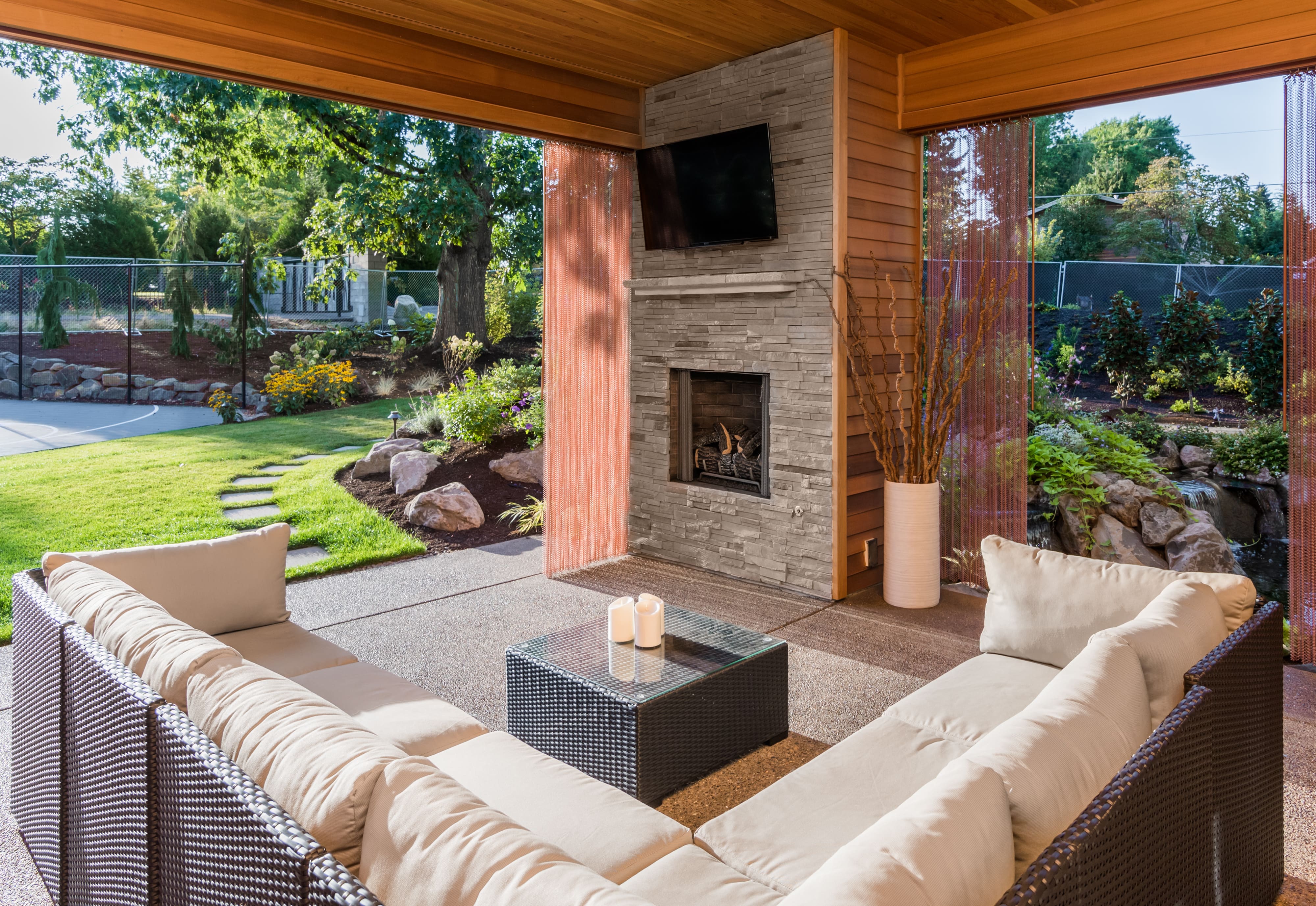 A covered patio with a living room setup and a fireplace