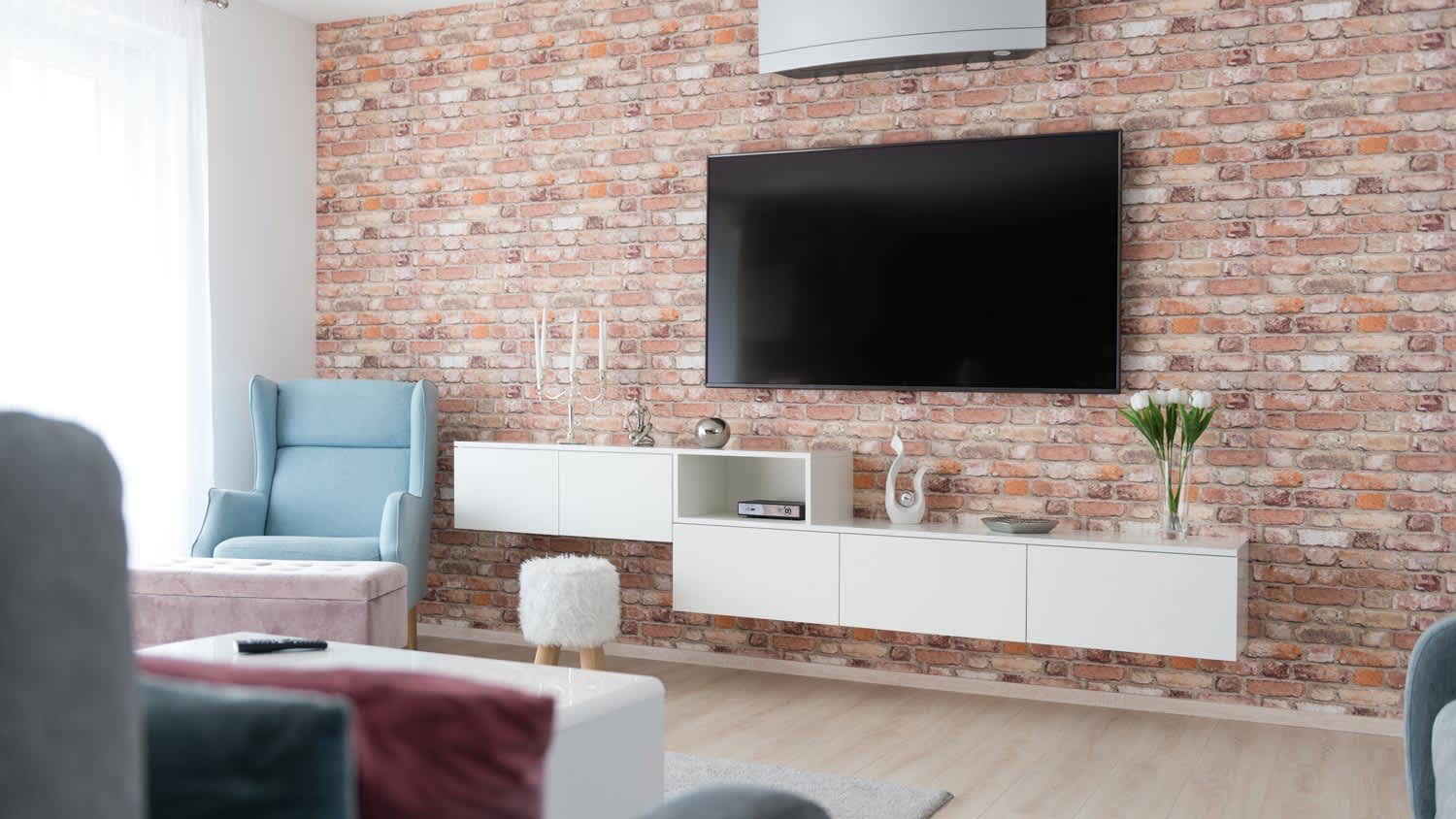 A living room with a mounted TV on a brick wall