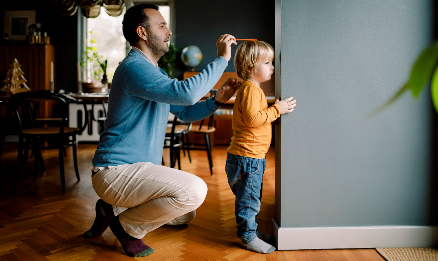 A father measuring daughter’s heigh against house wall