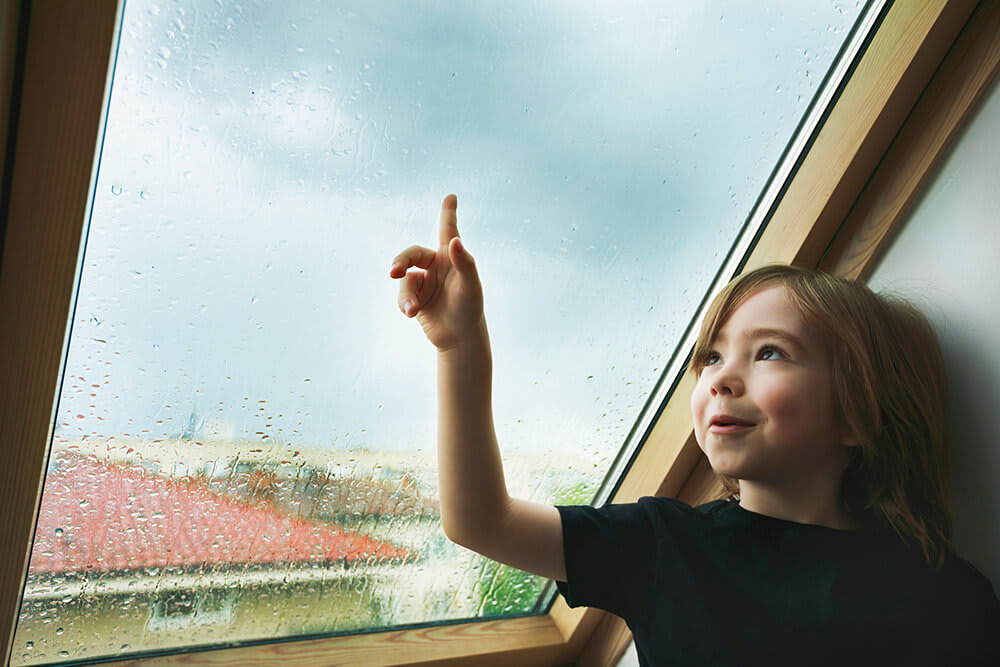 Child watching the rain from a rooftop window
