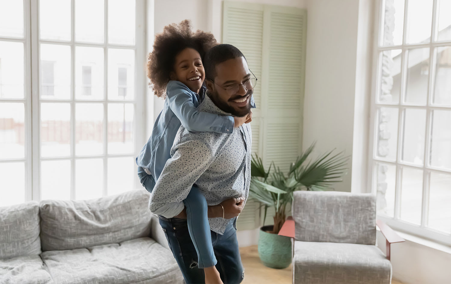 Father piggyback riding his daughter in the living room