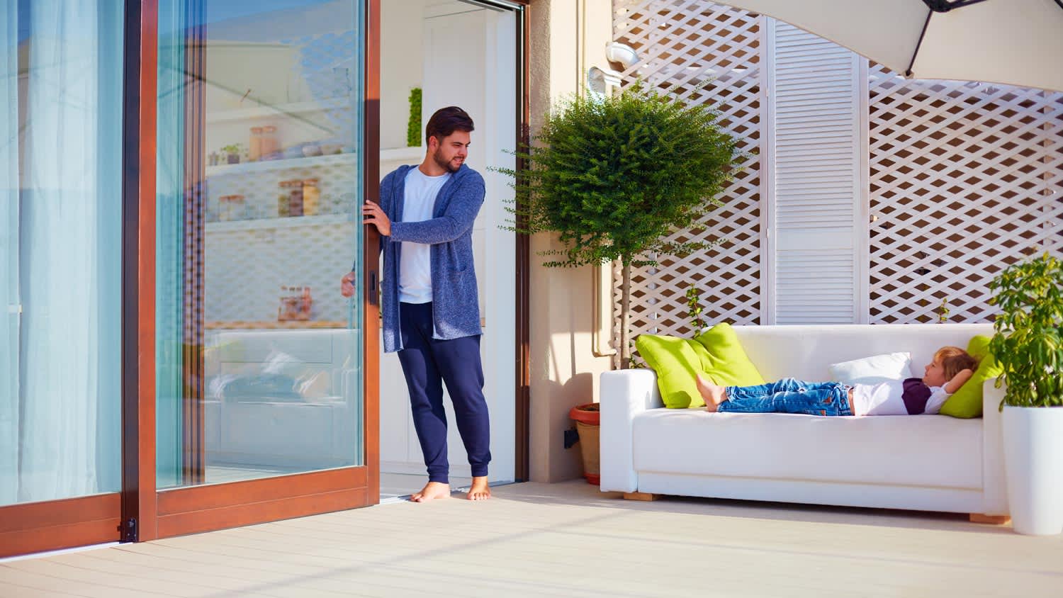 A man opening a sliding glass door leading to the patio