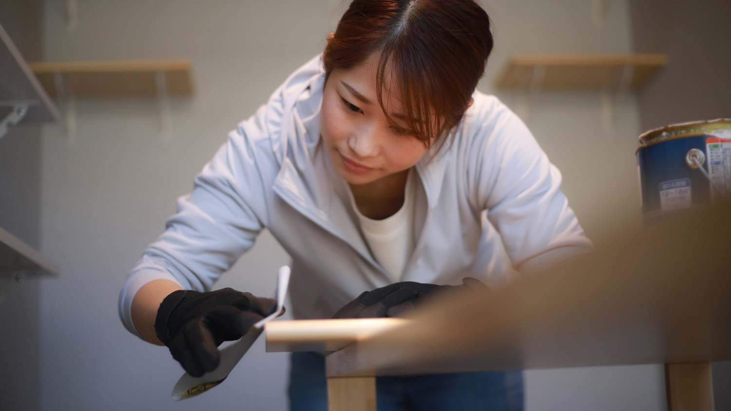 A woman refinishing a wooden table