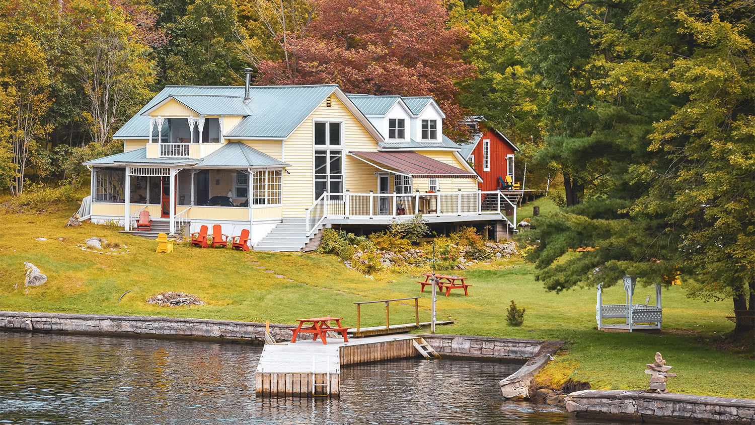 house by the water surrounded by trees in autumn