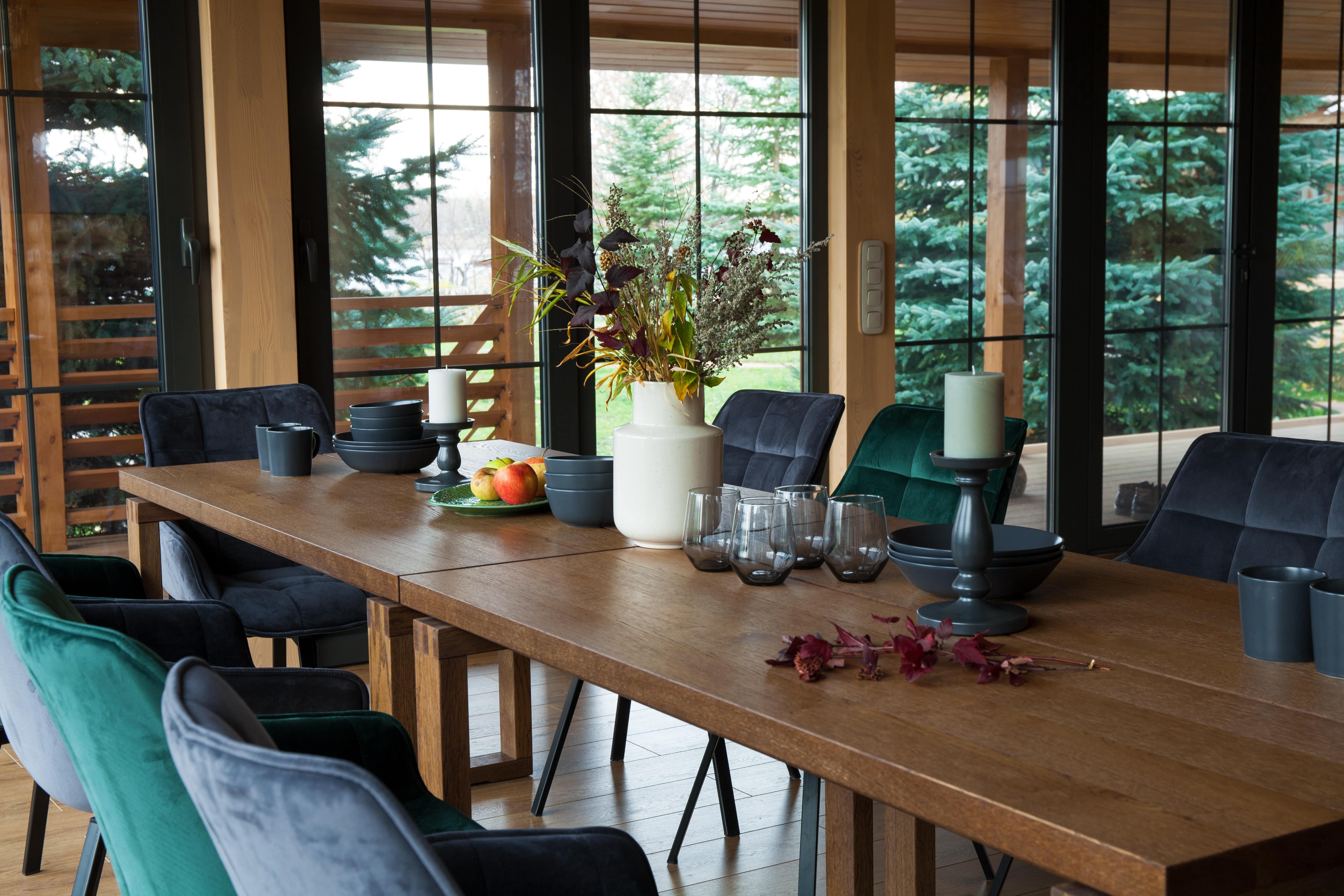 Country house dining room interior with wooden table and green and gray velvet chairs