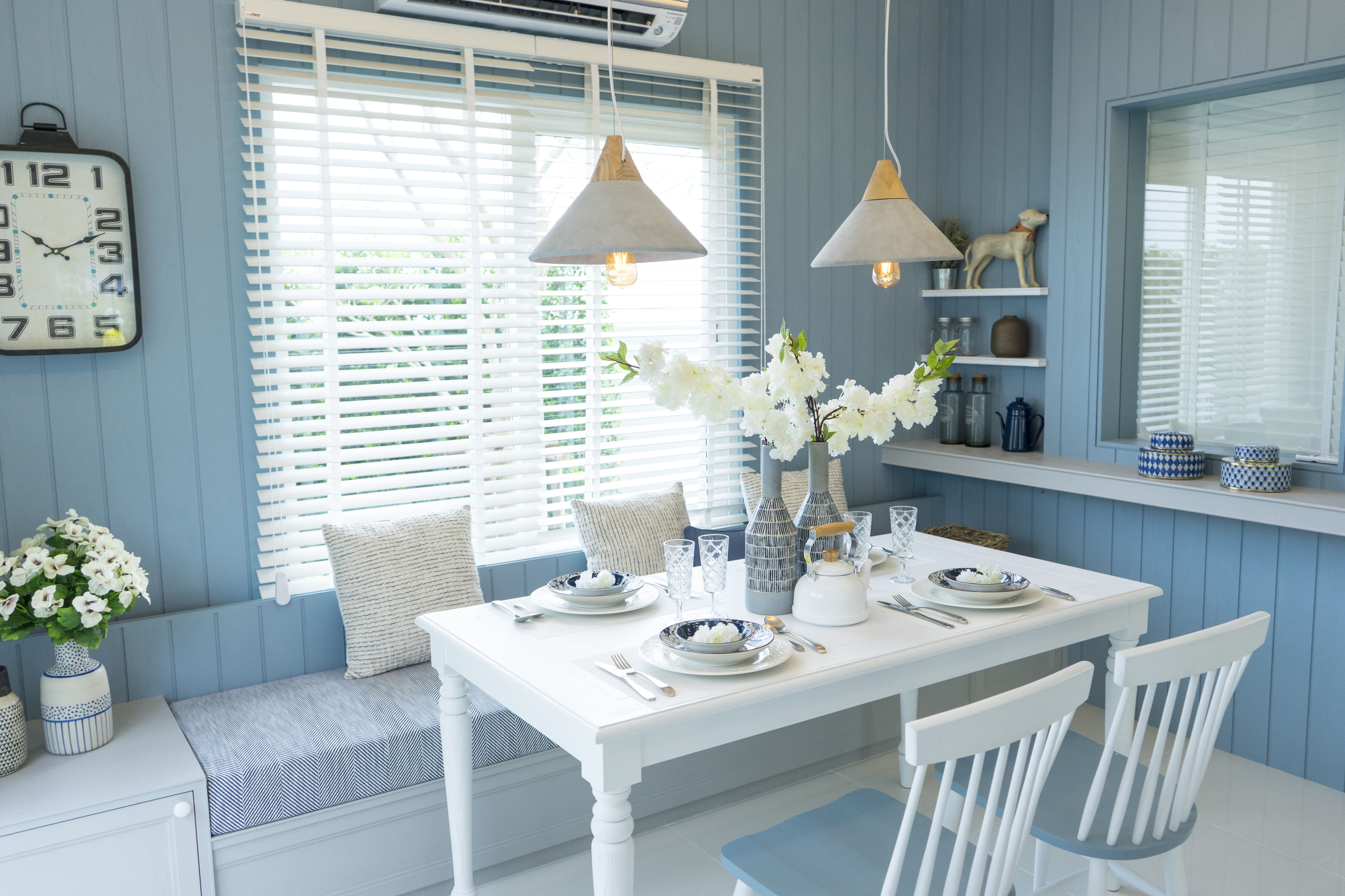 Beachy dining room with blue shiplap walls and built-ins, blue banquette, and white dining table
