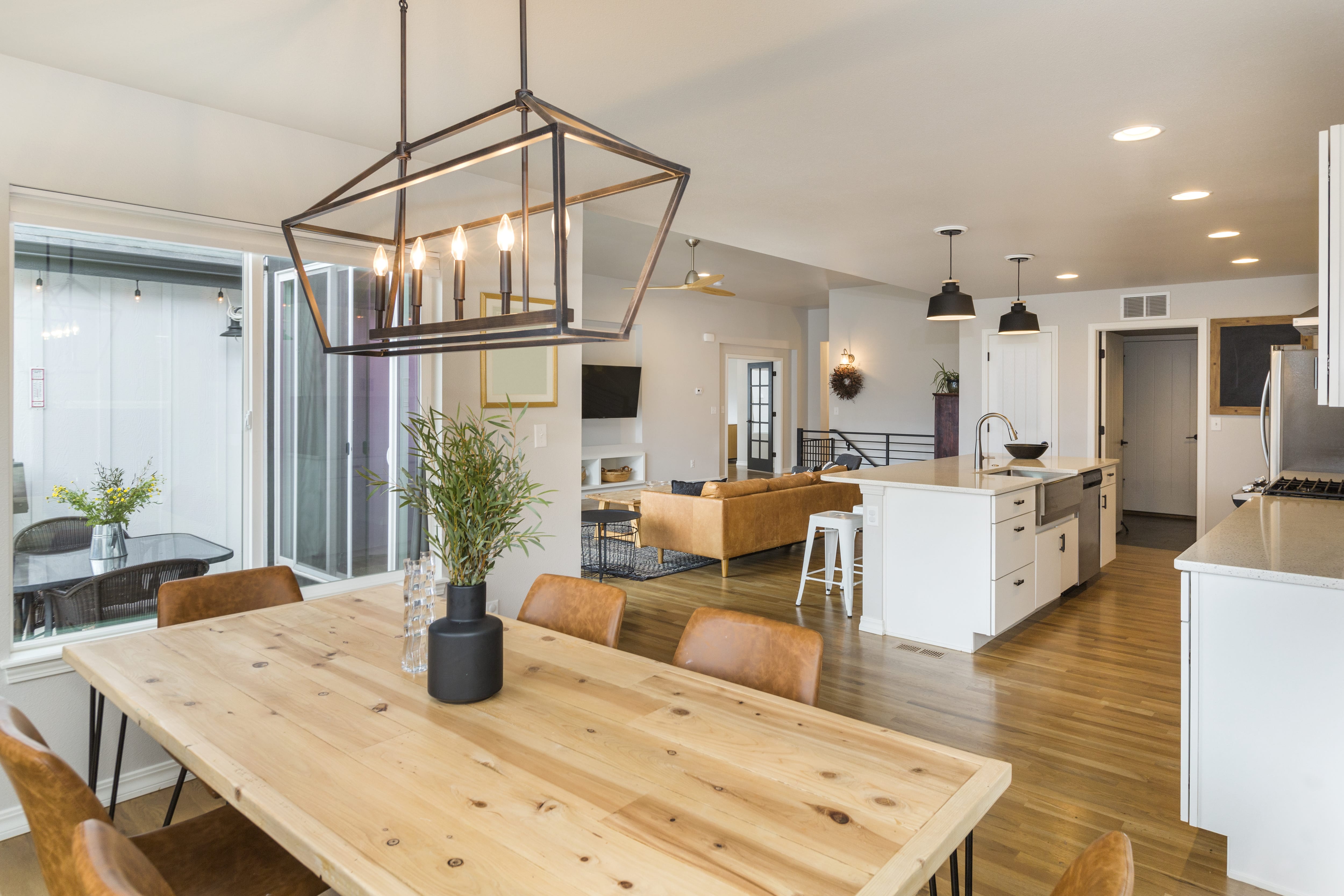 Modern farmhouse dining room with rustic wood table, leather chairs, and modern candelabra chandelier
