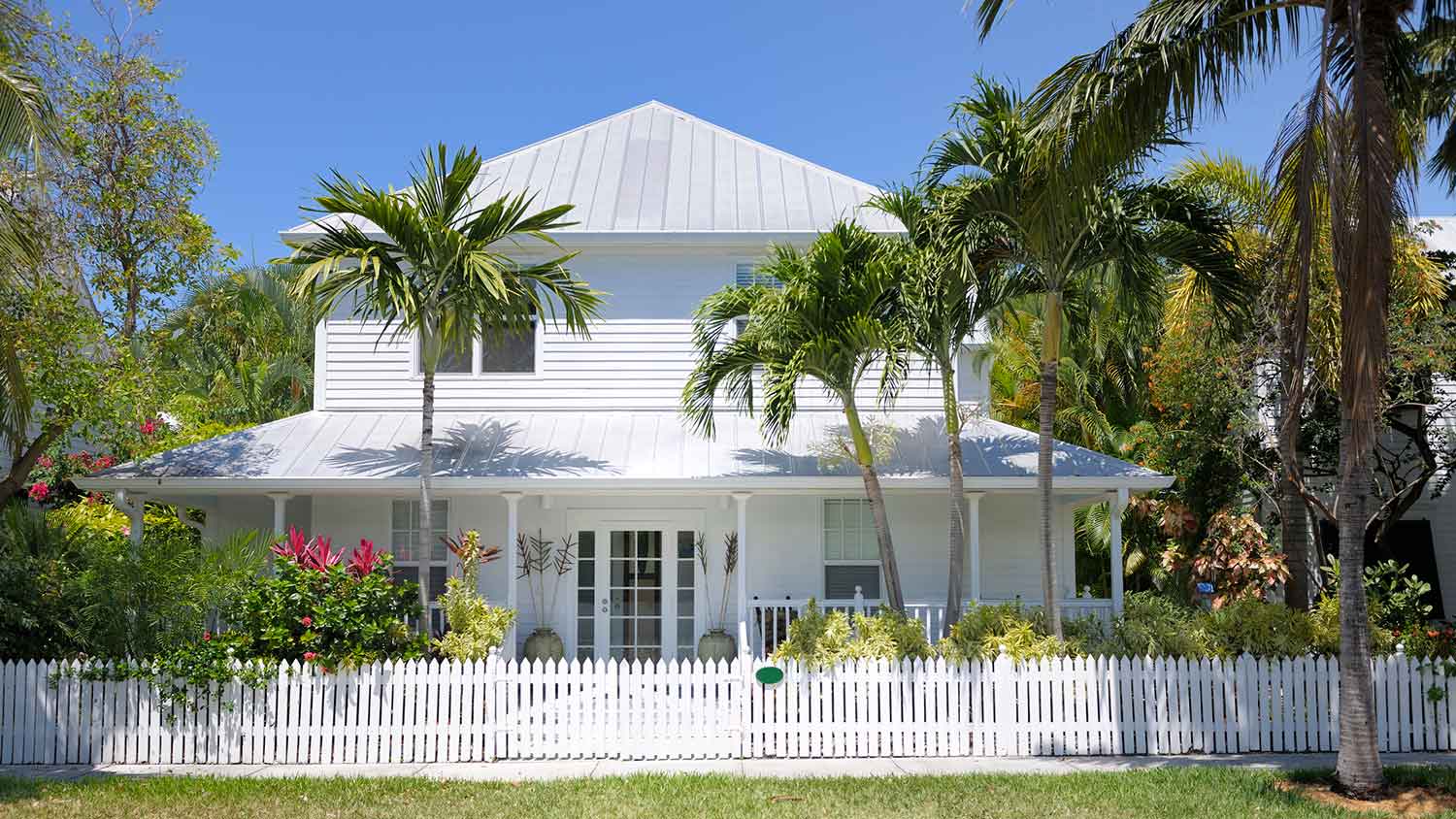 Coastal suburban house with white fence and palm trees