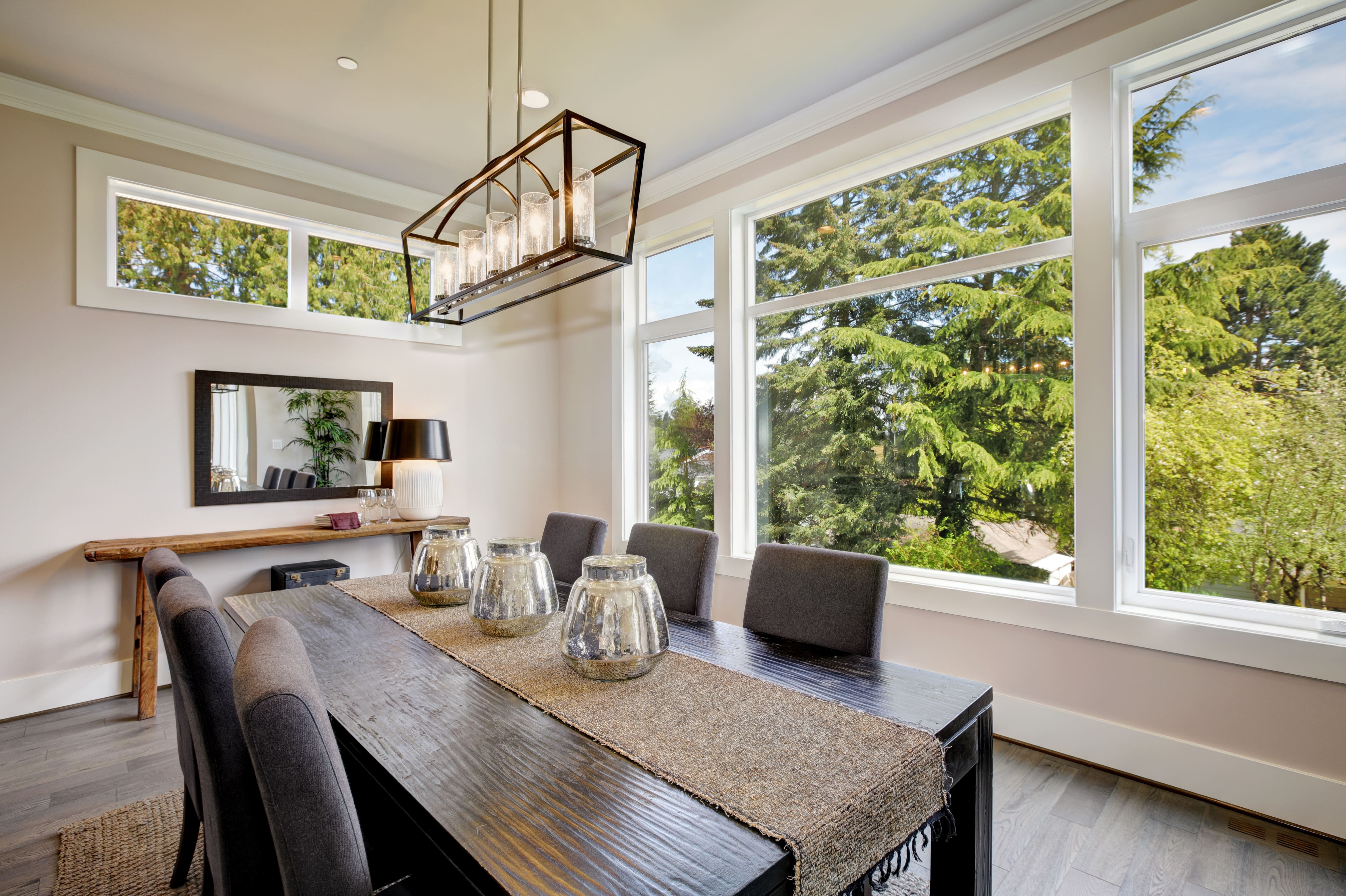 A black and brown dining room with a black rectangular cage chandelier