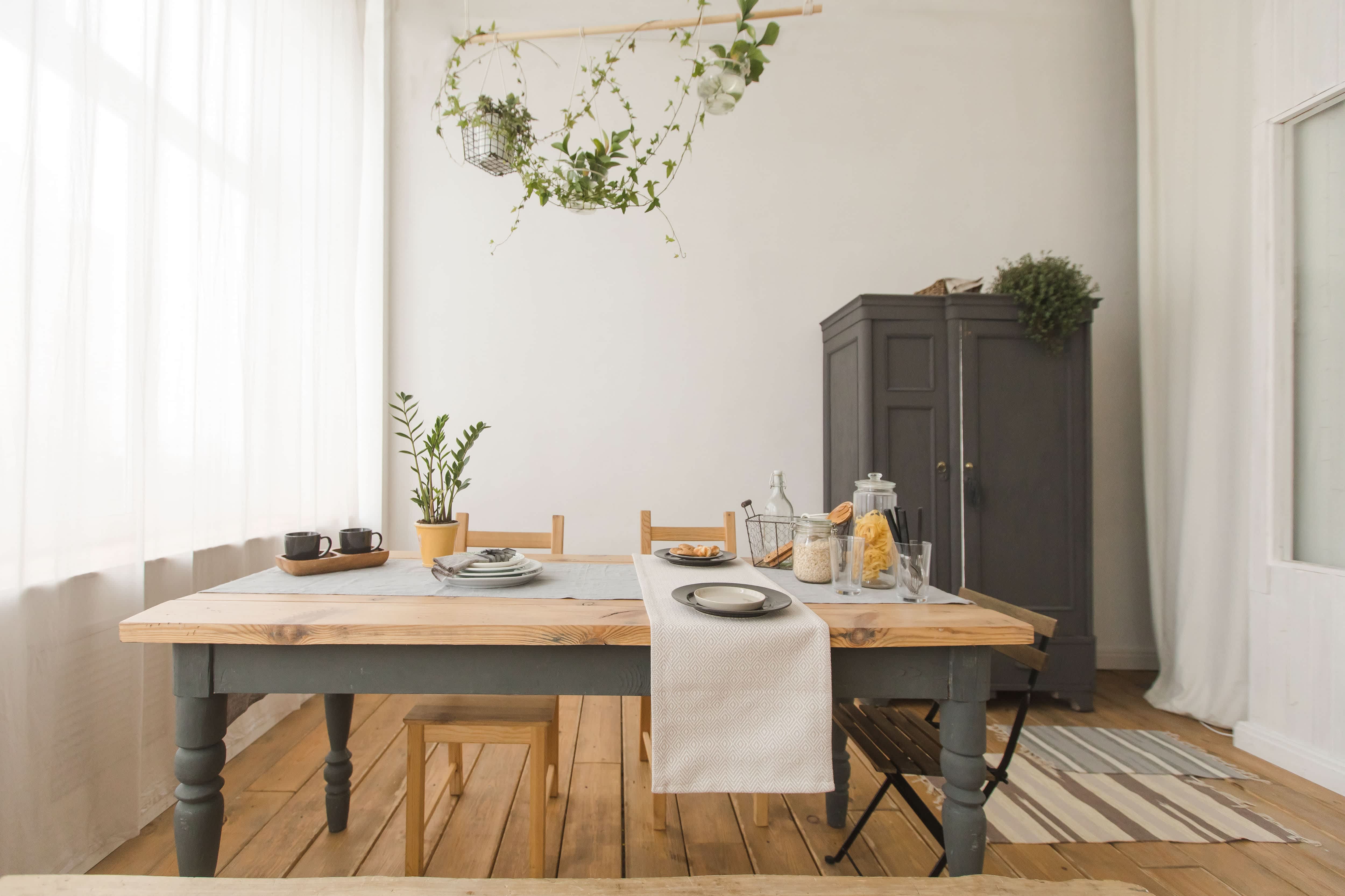 Green hanging plant above a gray and wood dining room table with table decor