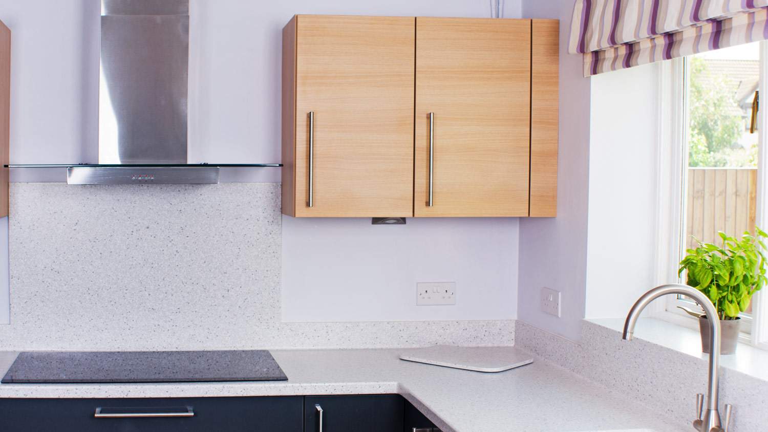 A modern kitchen with grey cupboards, oak cabinets and laminate countertop