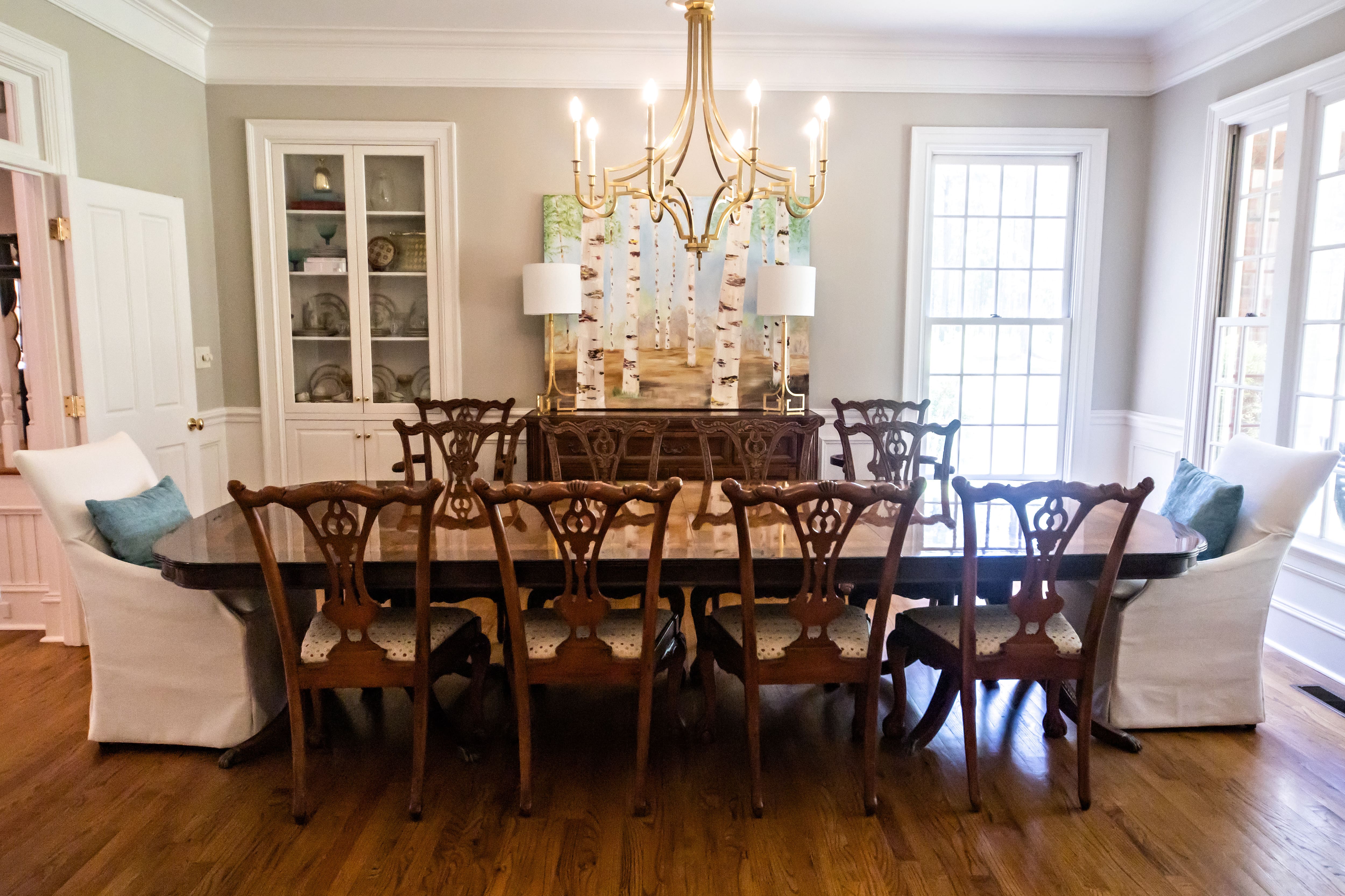 Large formal dining room with long wooden table, eight wood chairs, and two stuffed armless chairs