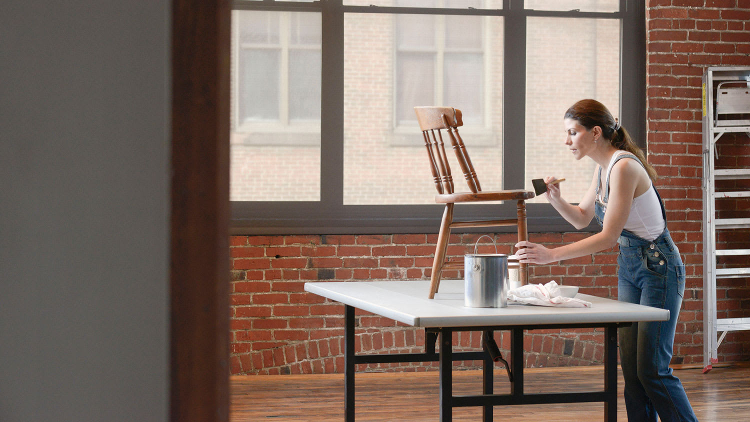 Woman in her studio is vanishing a wooden chair