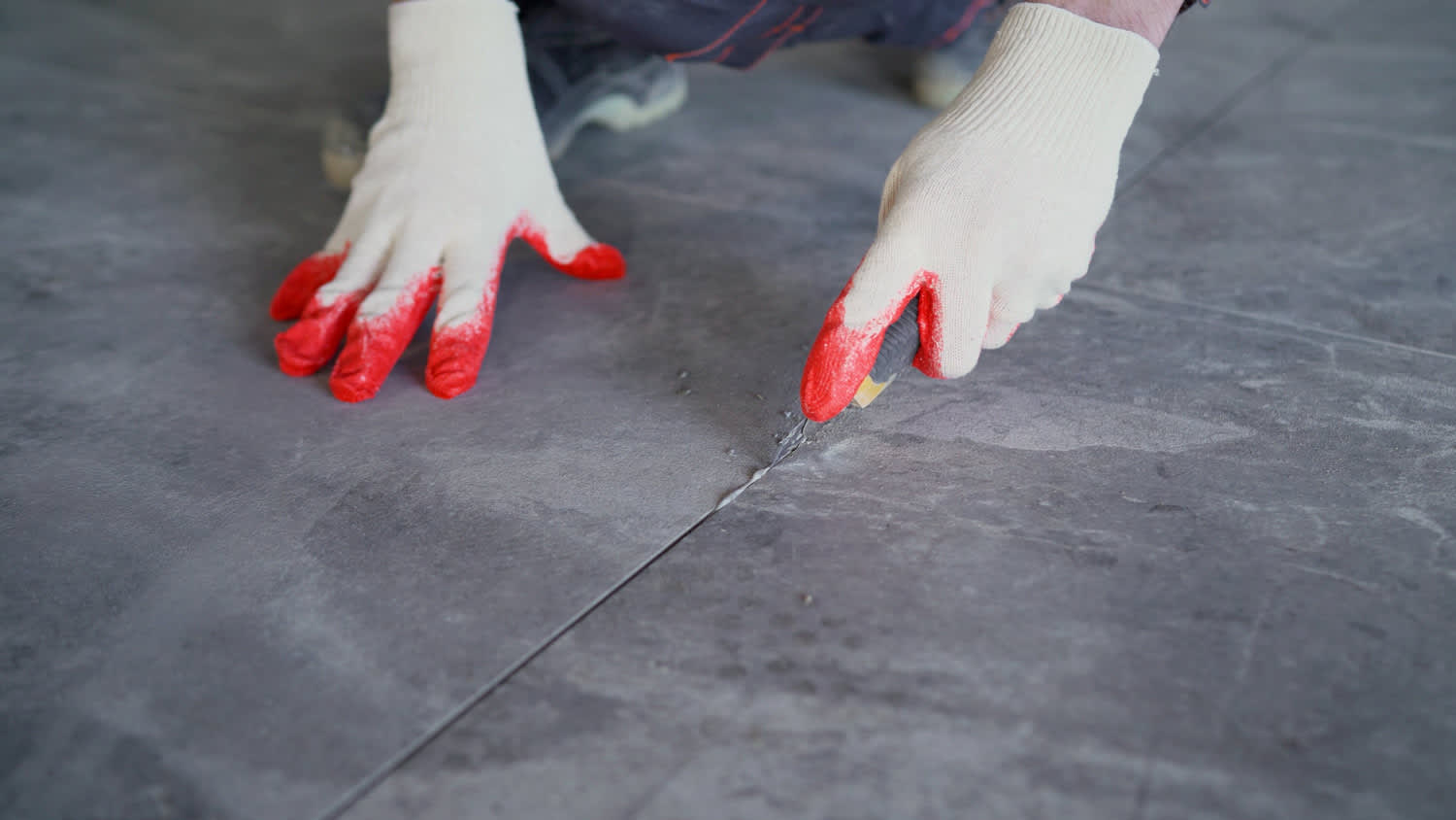 Close-up of a worker removing old grout between ceramic tiles
