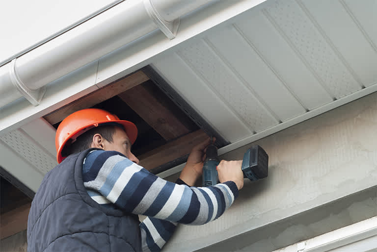 Repairman fixing soffit of house