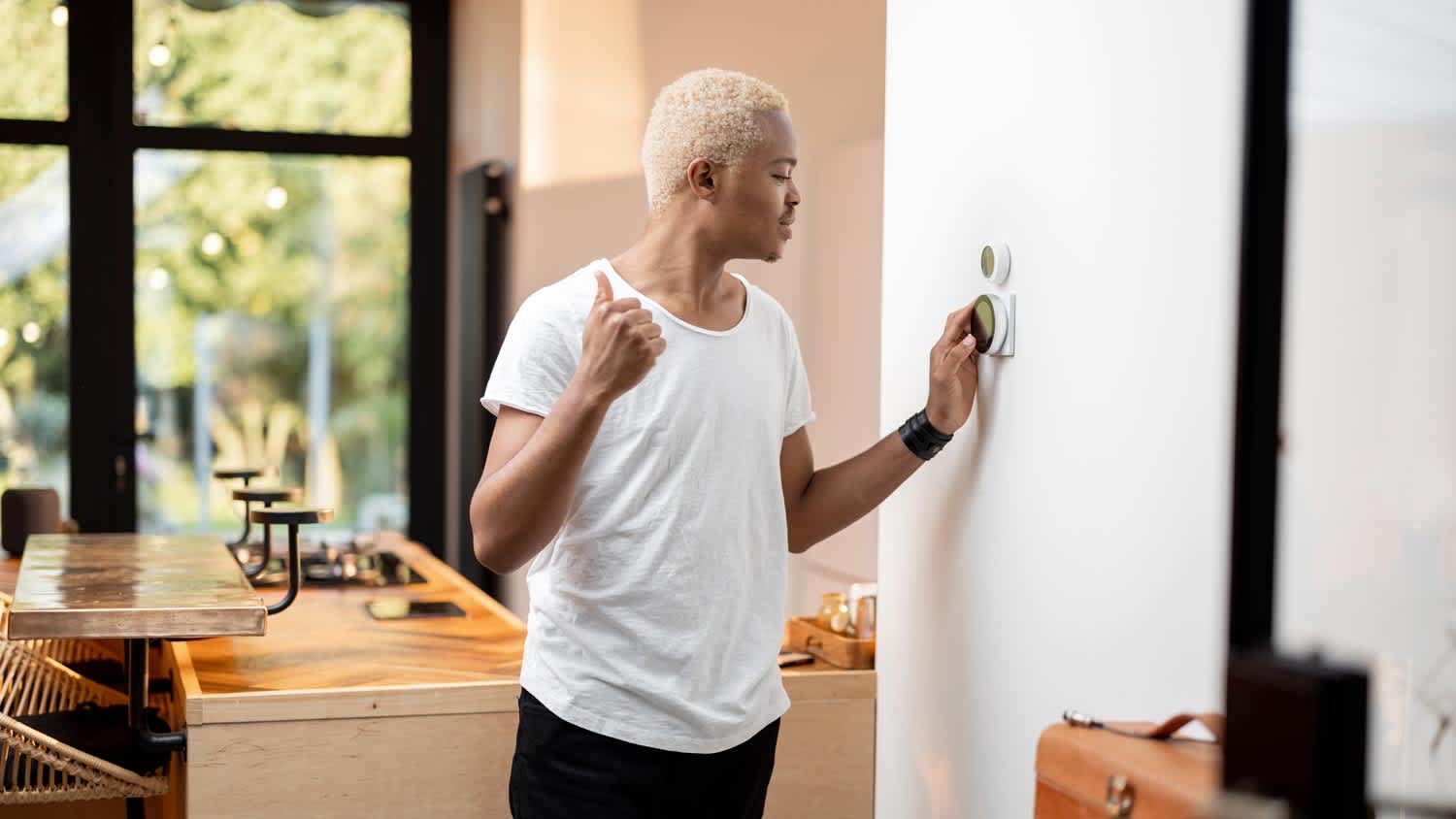 A young man turning on the thermostat