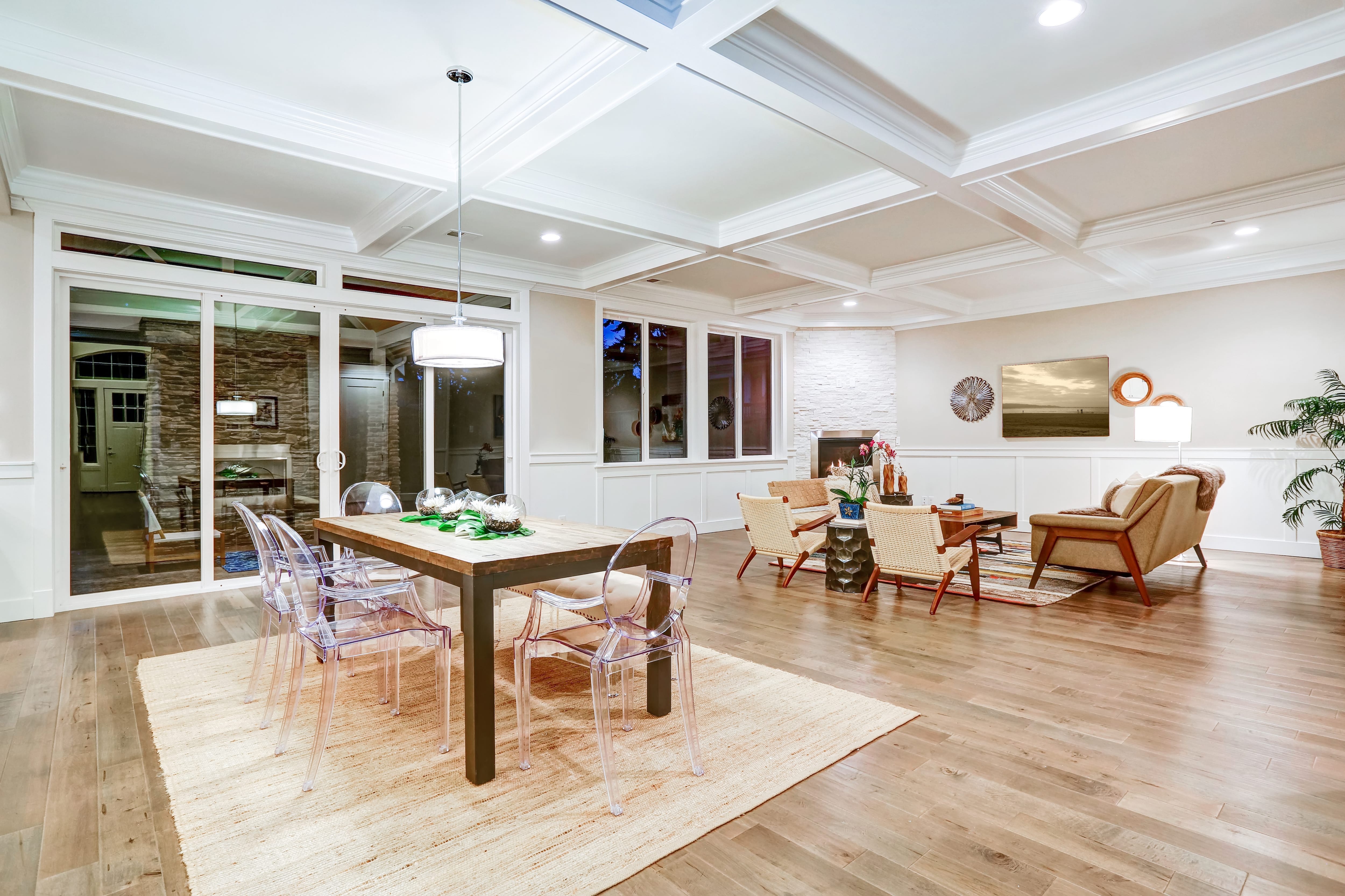 Craftsman style dining room with coffered ceiling, wood table, and clear plastic ghost chairs